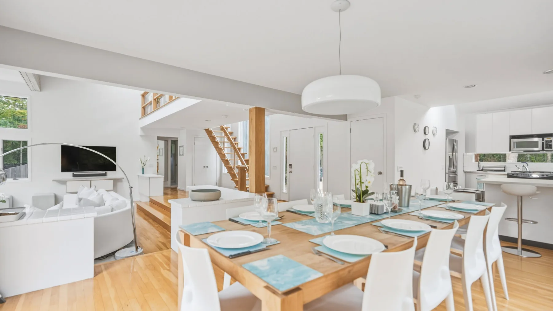 A bright open-plan living and dining area with a wooden dining table and kitchen.