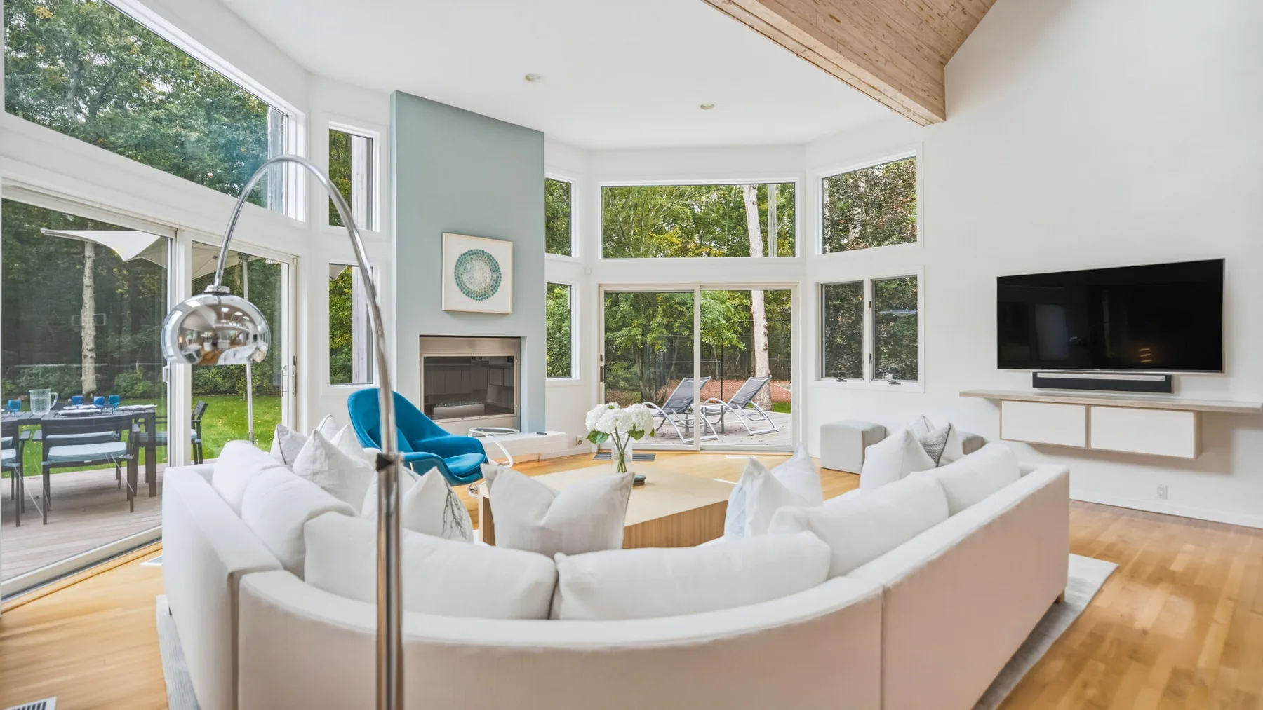 A bright living room with curved seating, a fireplace, and large windows.
