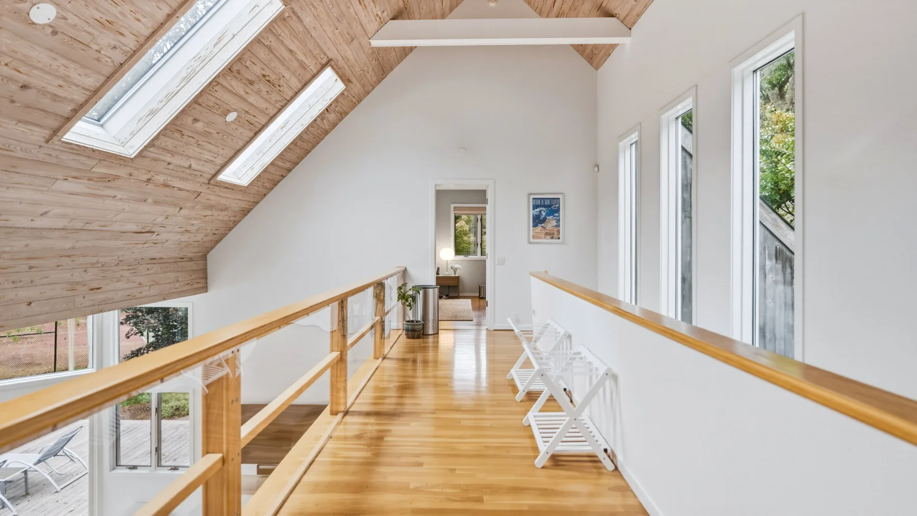 A bright upstairs hallway has a wood-paneled sloped ceiling and a bench.
