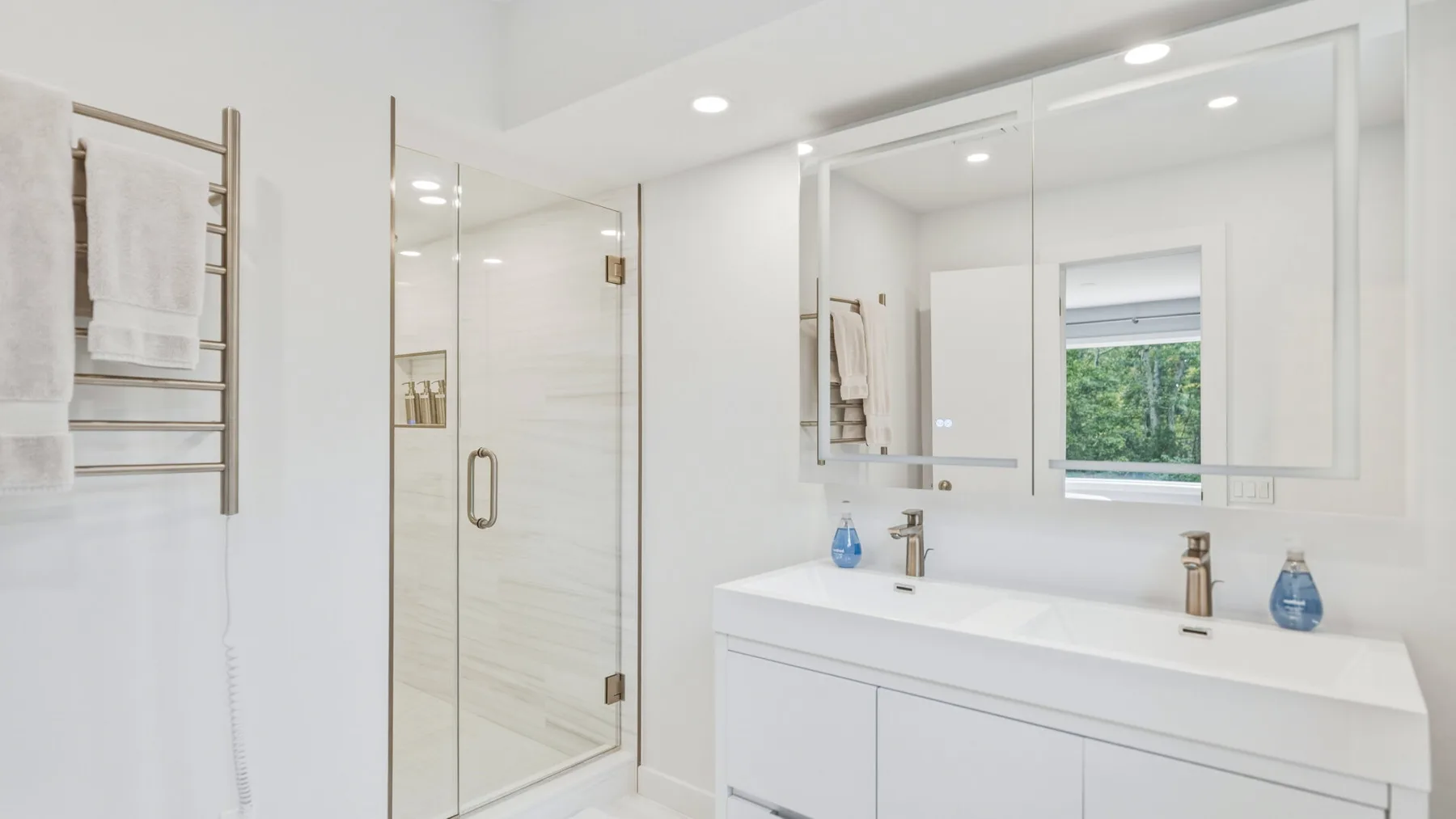 A bright bathroom with a glass shower and a wide vanity.
