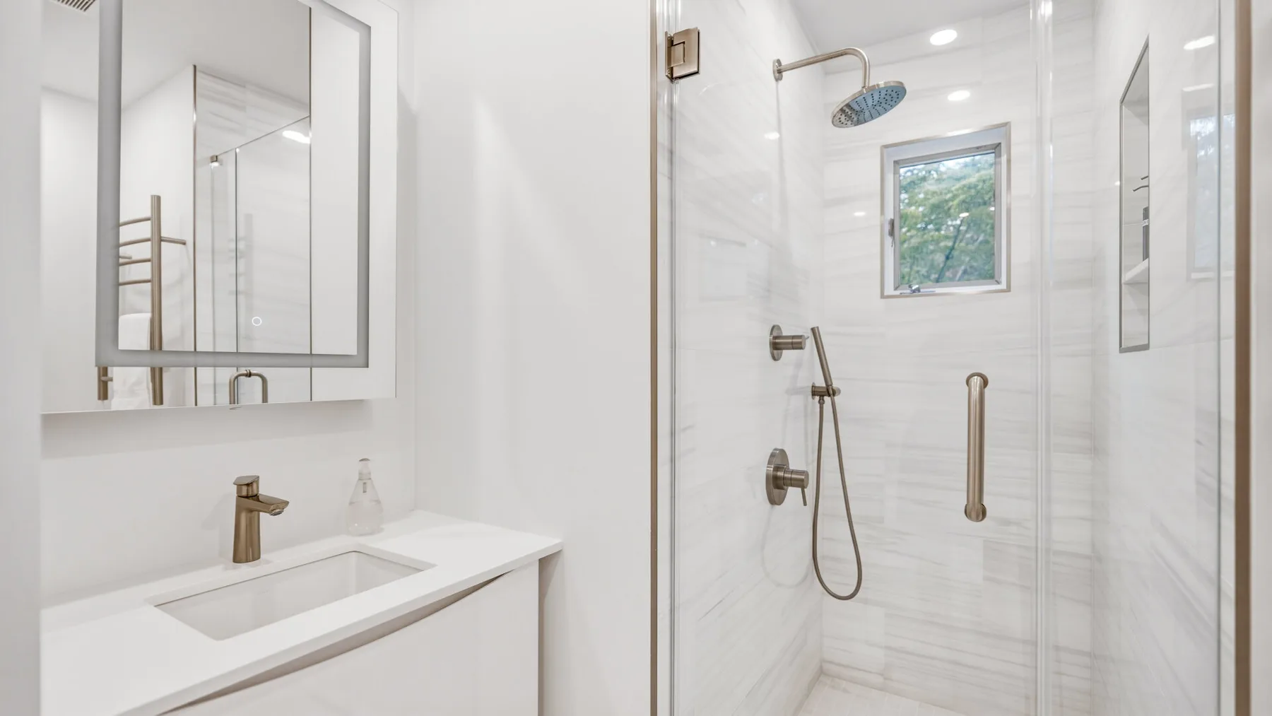 A bright bathroom with a white vanity and glass-enclosed shower.