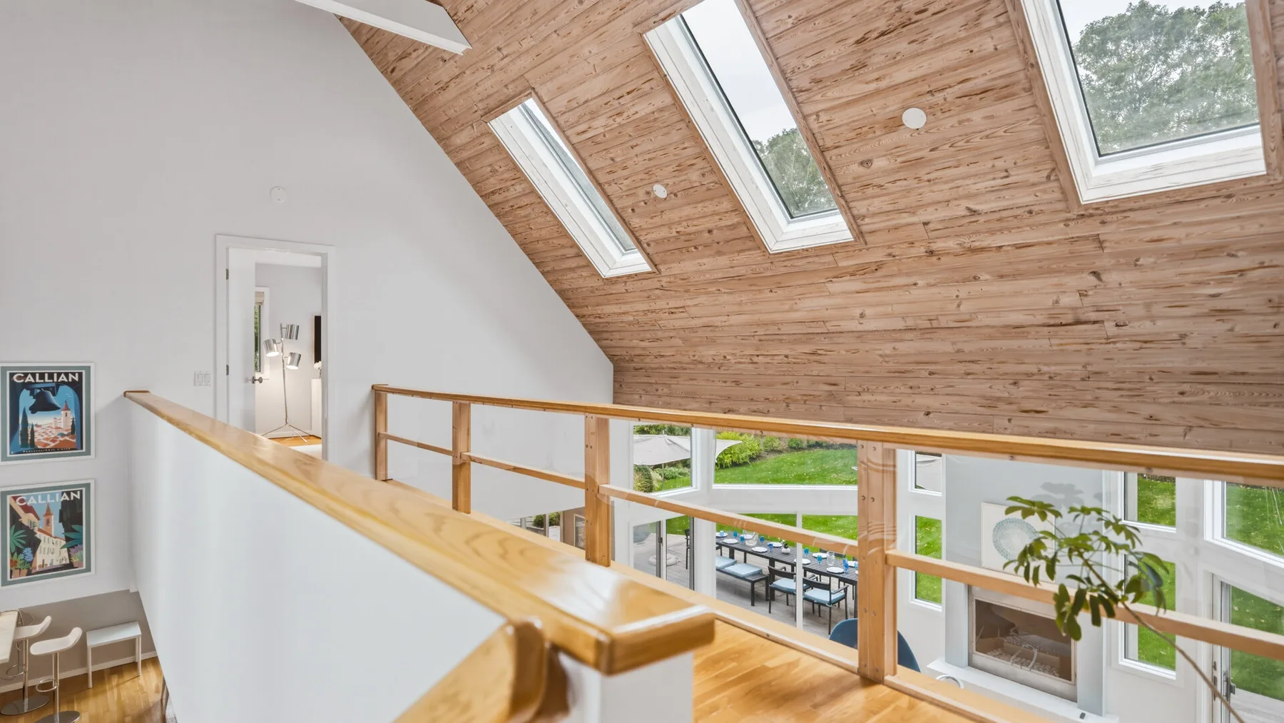 A bright loft area with a wooden railing and large skylights.