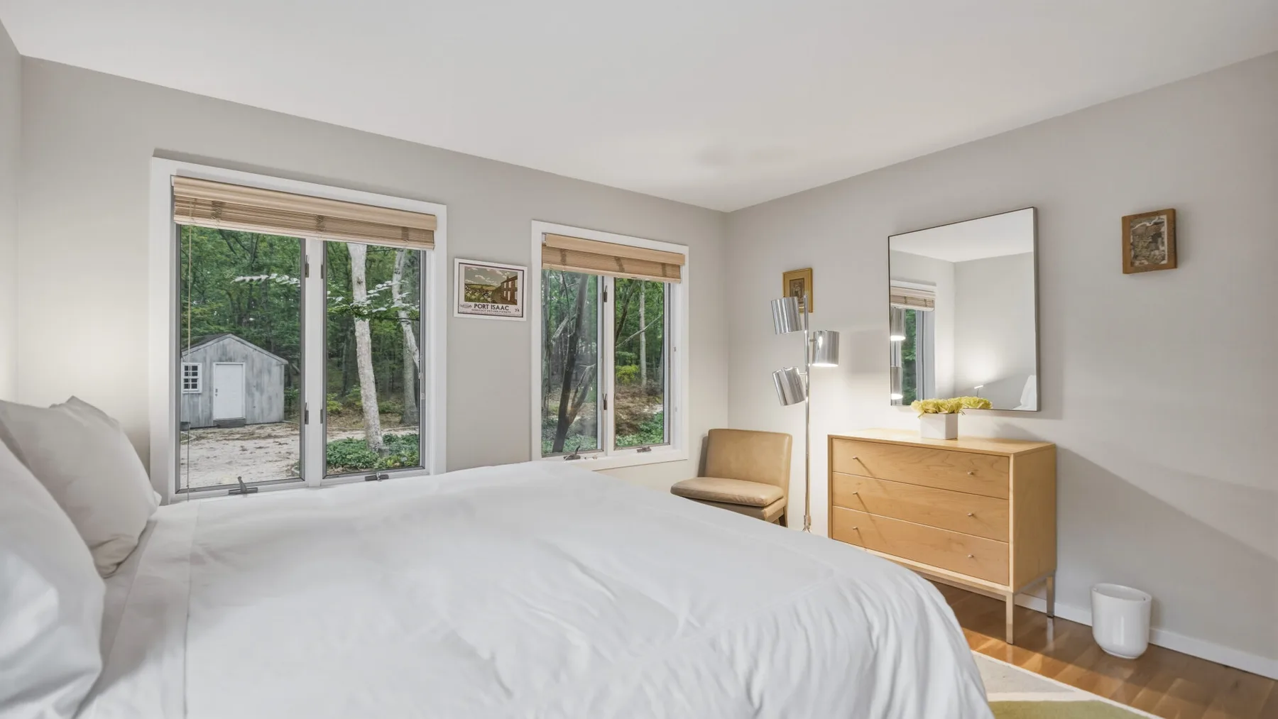 A bedroom with a large bed, two windows, and a wooden dresser.
