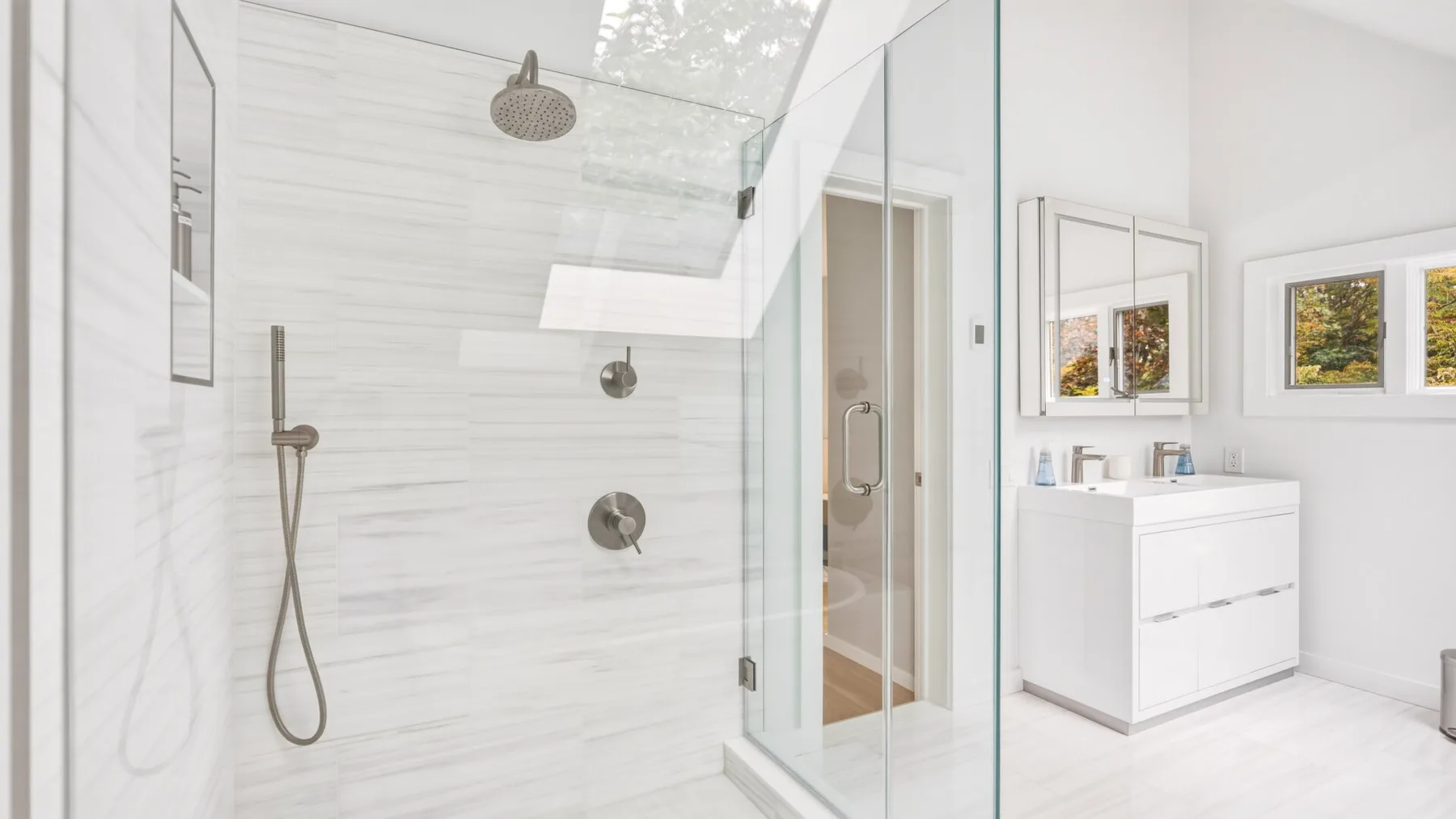 A bright bathroom with a glass shower and a white vanity.