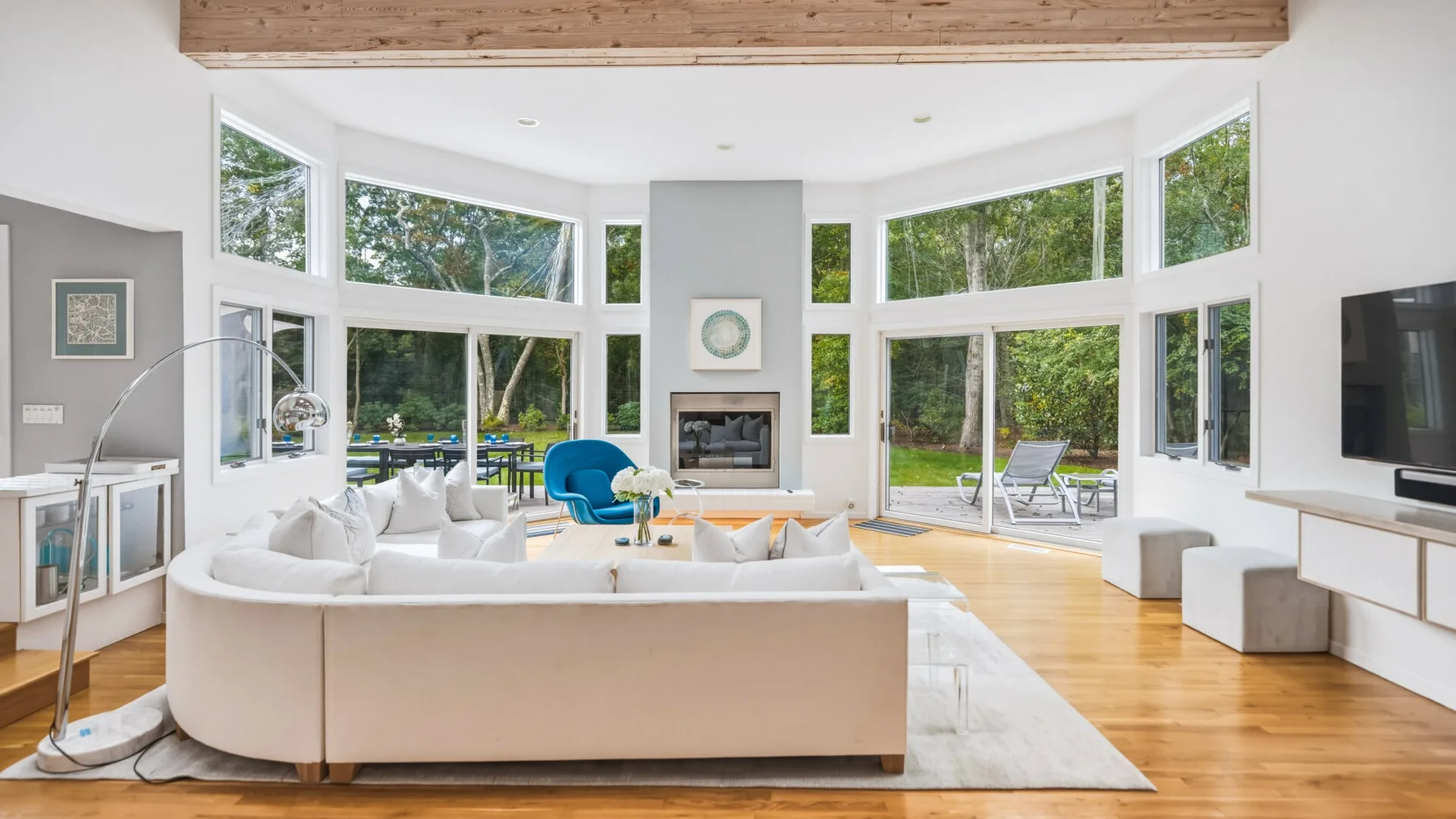 A bright living room with wide windows, seating, and a fireplace.