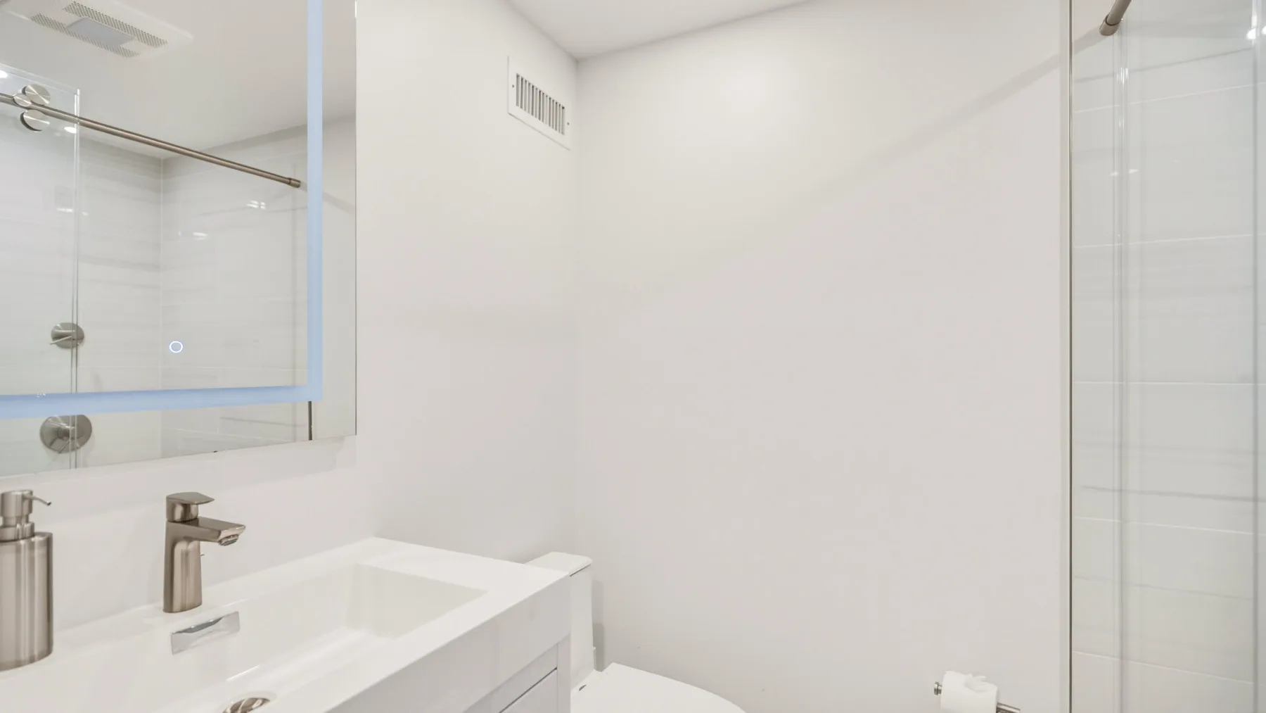 A bright bathroom with a white vanity and a glass shower.