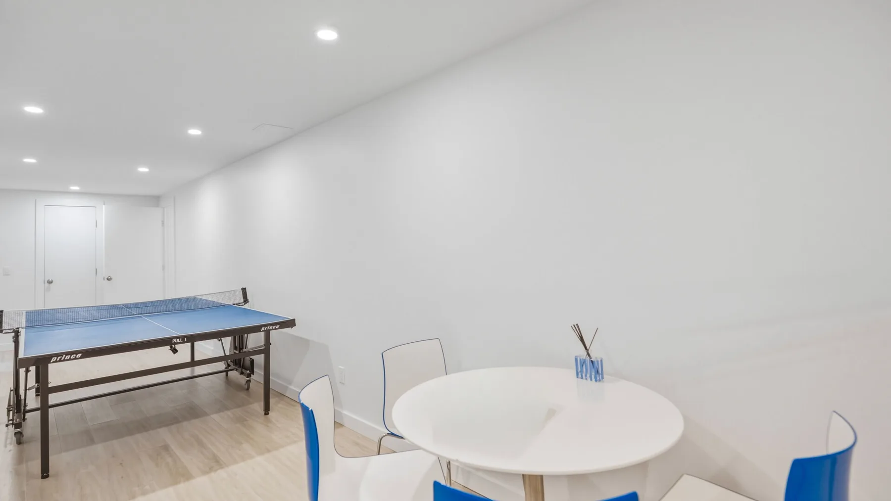 A bright recreation room with a ping-pong table and a round table with chairs.