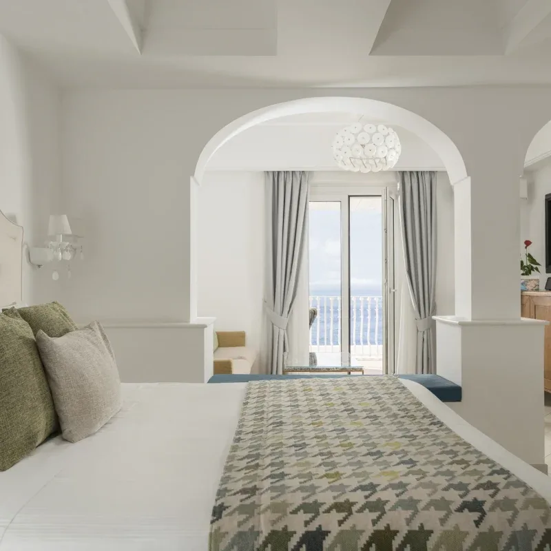 Bright hotel room with a large bed and balcony view.