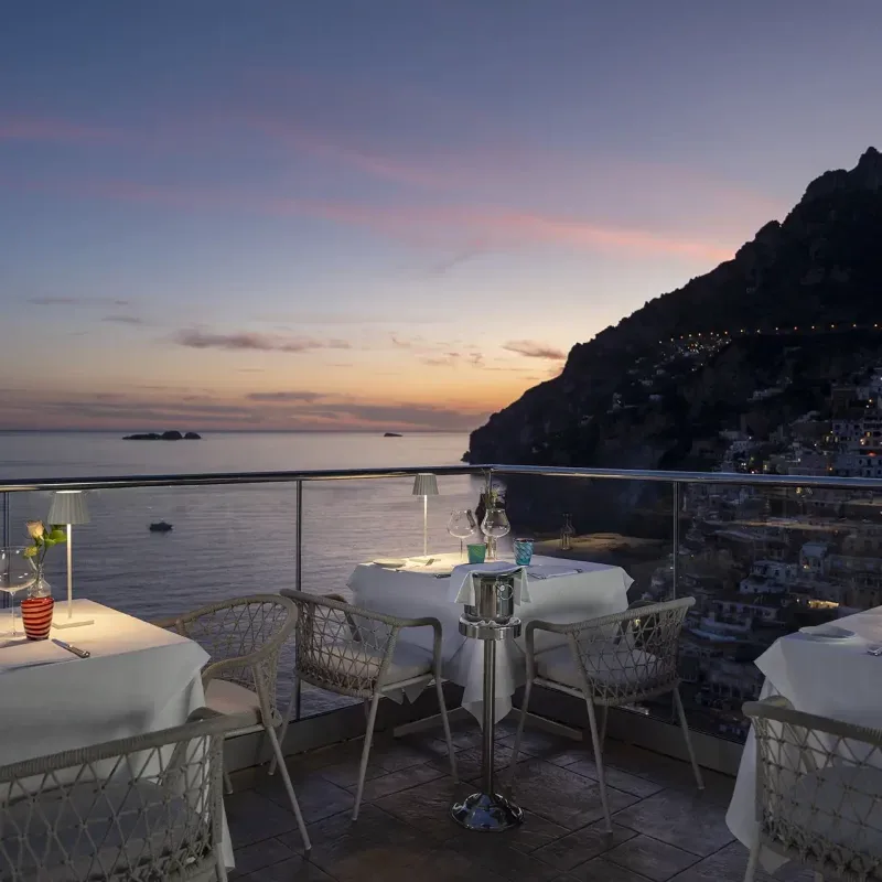 Terrace dining area overlooking the sea at sunset.