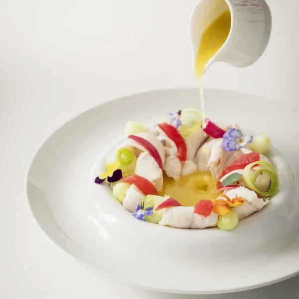 Seafood dish being finished with sauce.