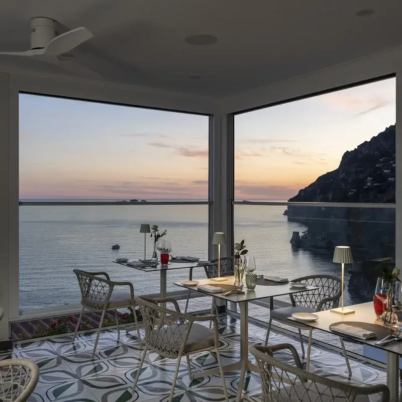 Seaside terrace with tables overlooking the coast at sunset.