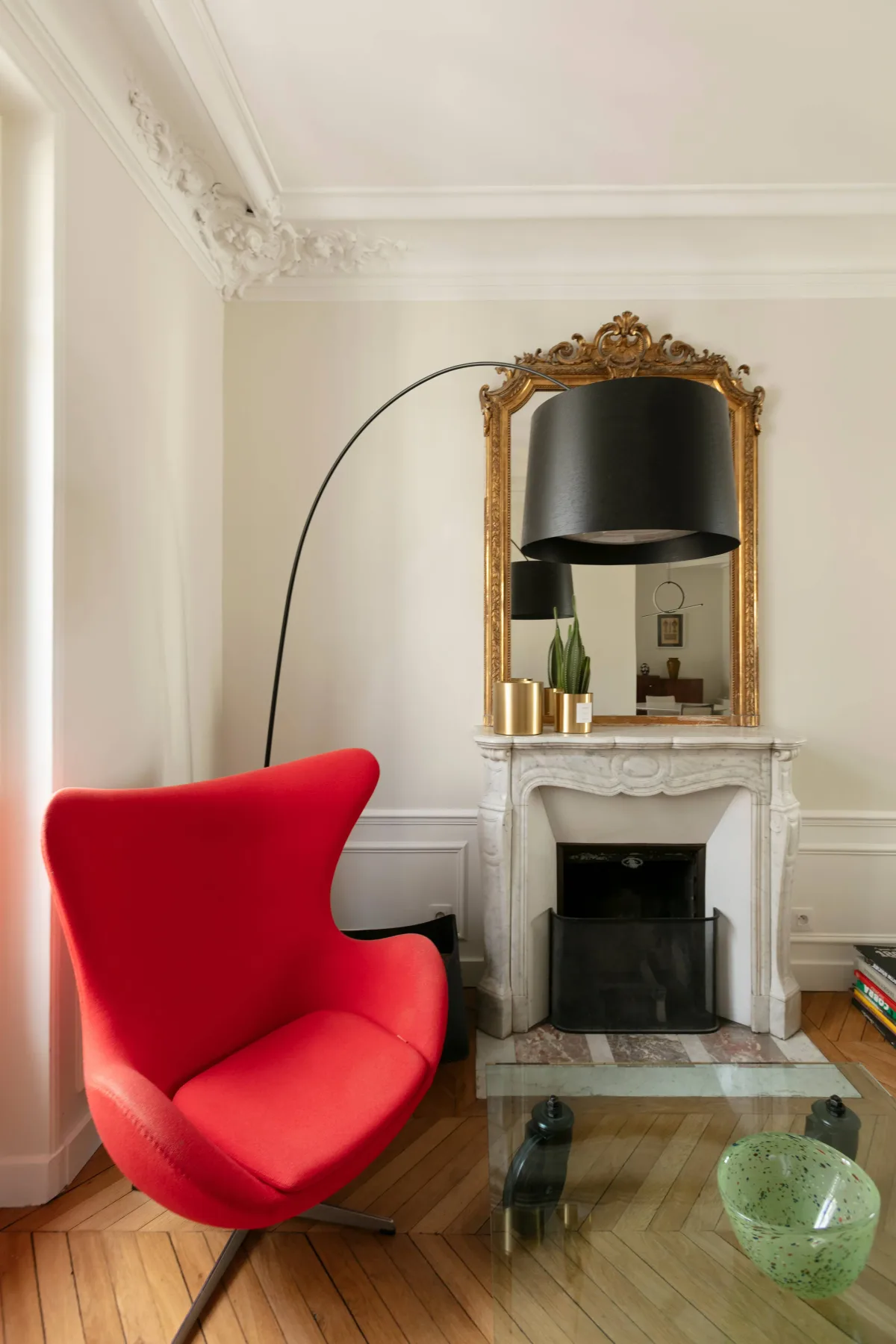 Una sala luminosa tiene un sillón rojo junto a una chimenea ornamentada.