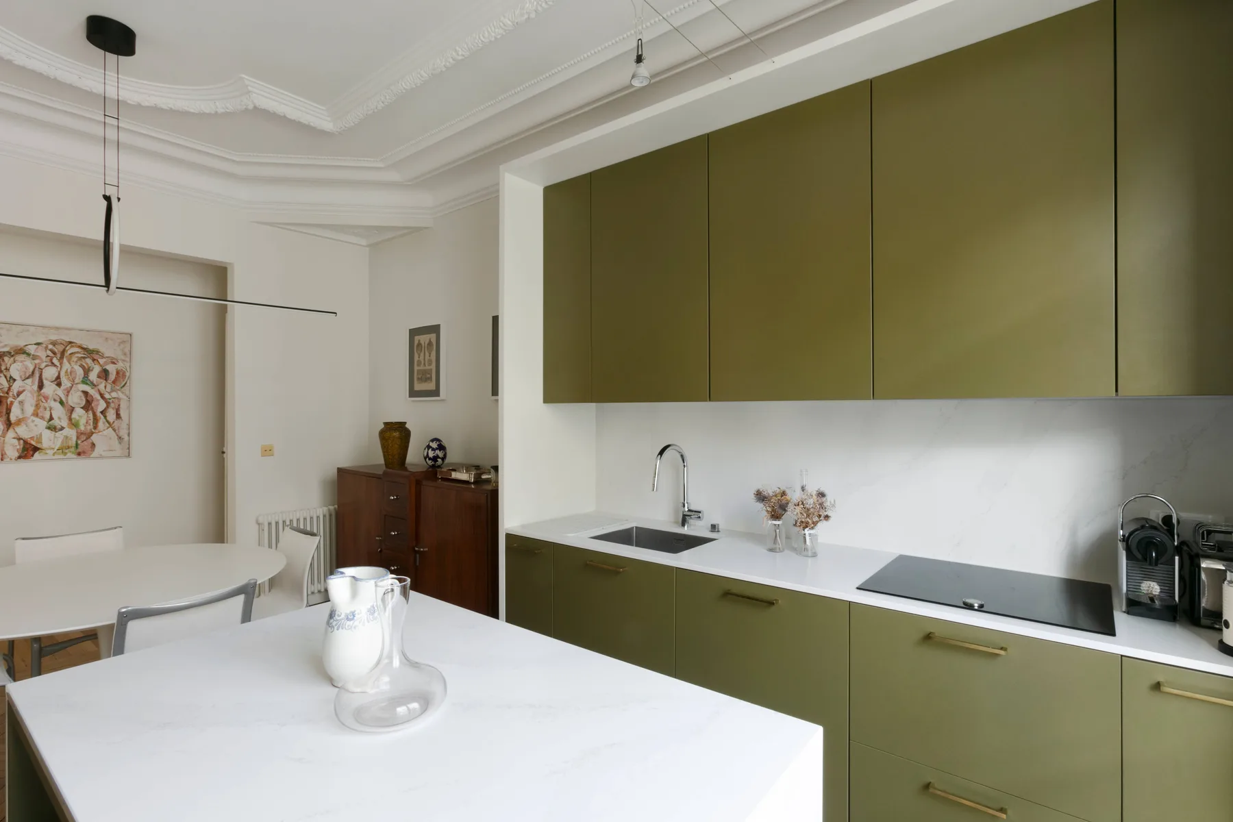 Una cocina moderna con gabinetes verde oliva y una isla blanca.