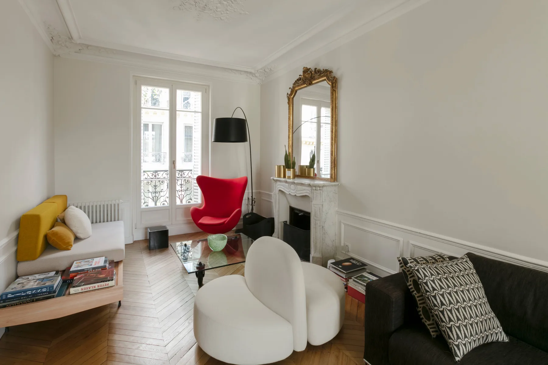 Una sala luminosa con un sillón rojo, asientos blancos y una chimenea.