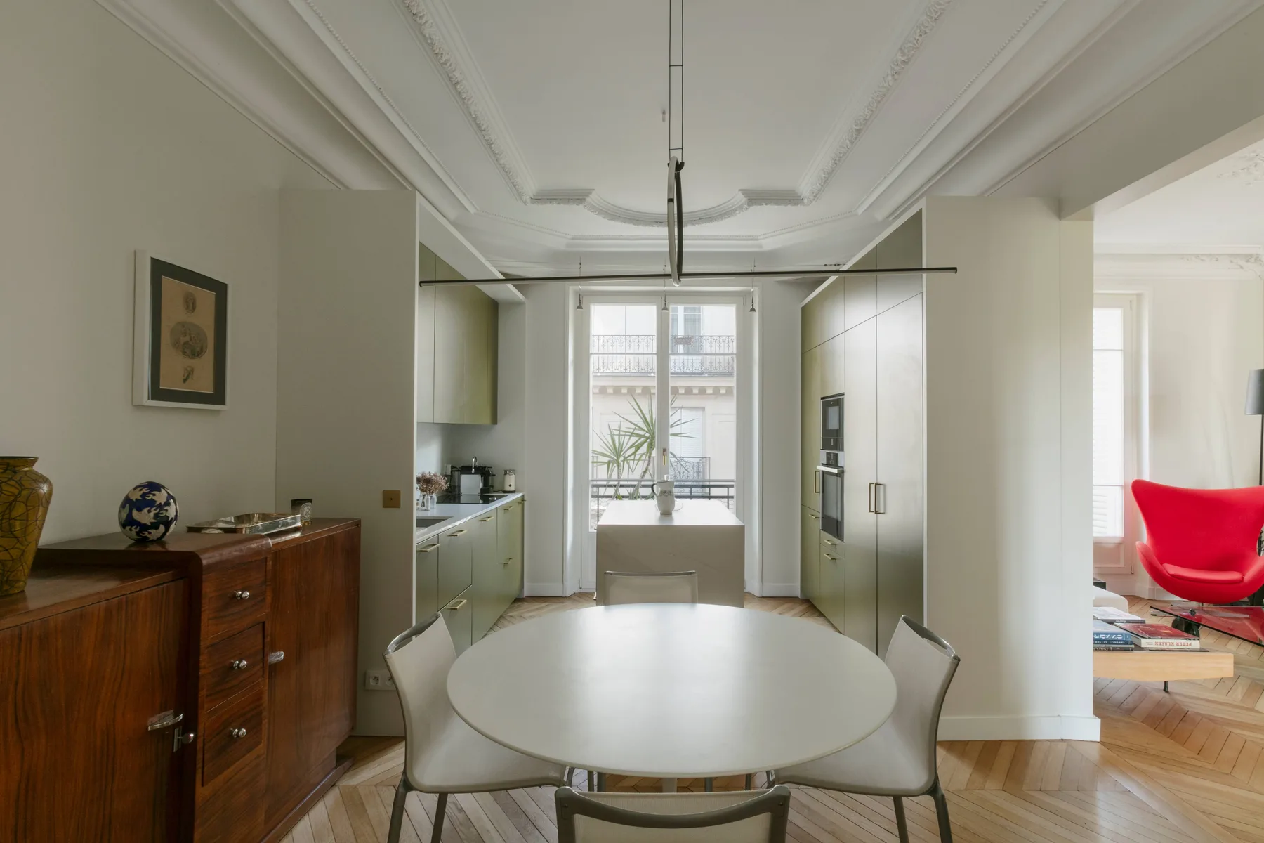 Un comedor luminoso con una mesa redonda junto a una cocina abierta y grandes ventanas.