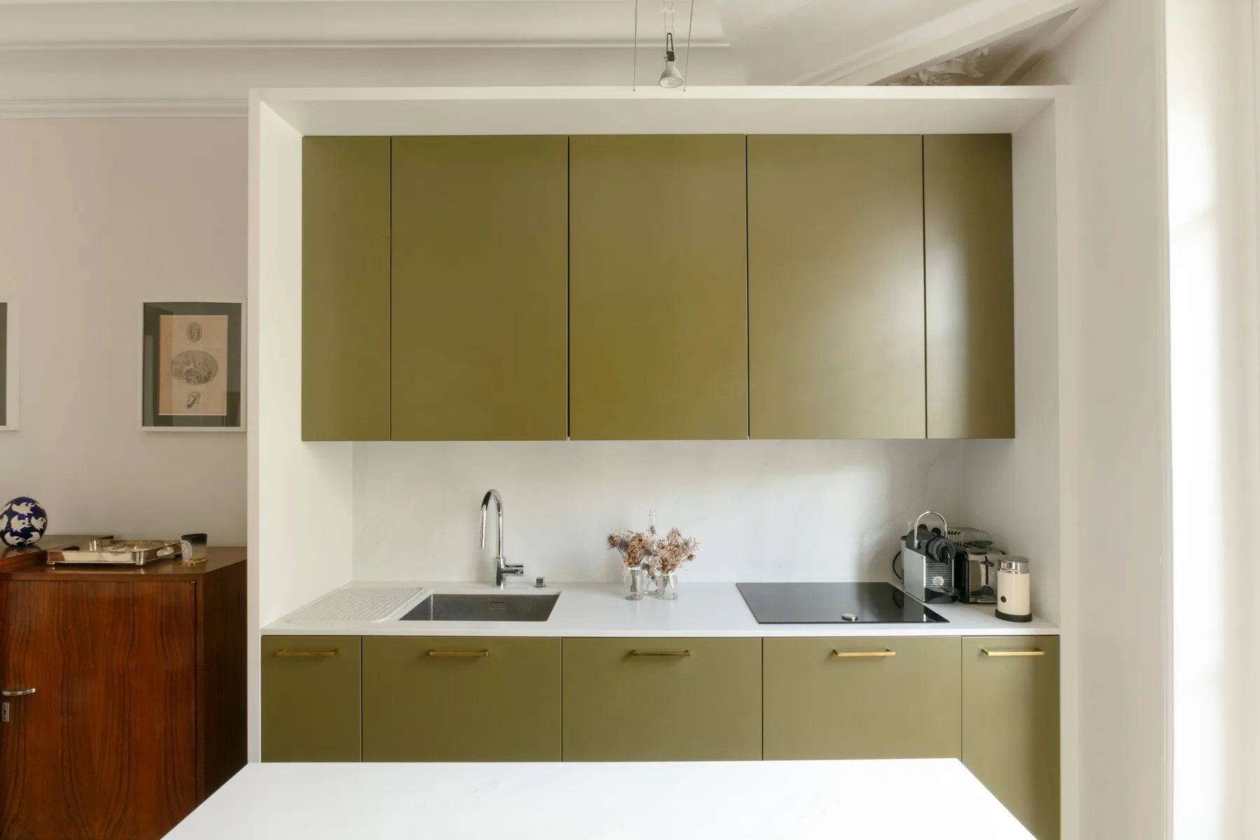 Una cocina moderna con gabinetes verde oliva y una encimera blanca.