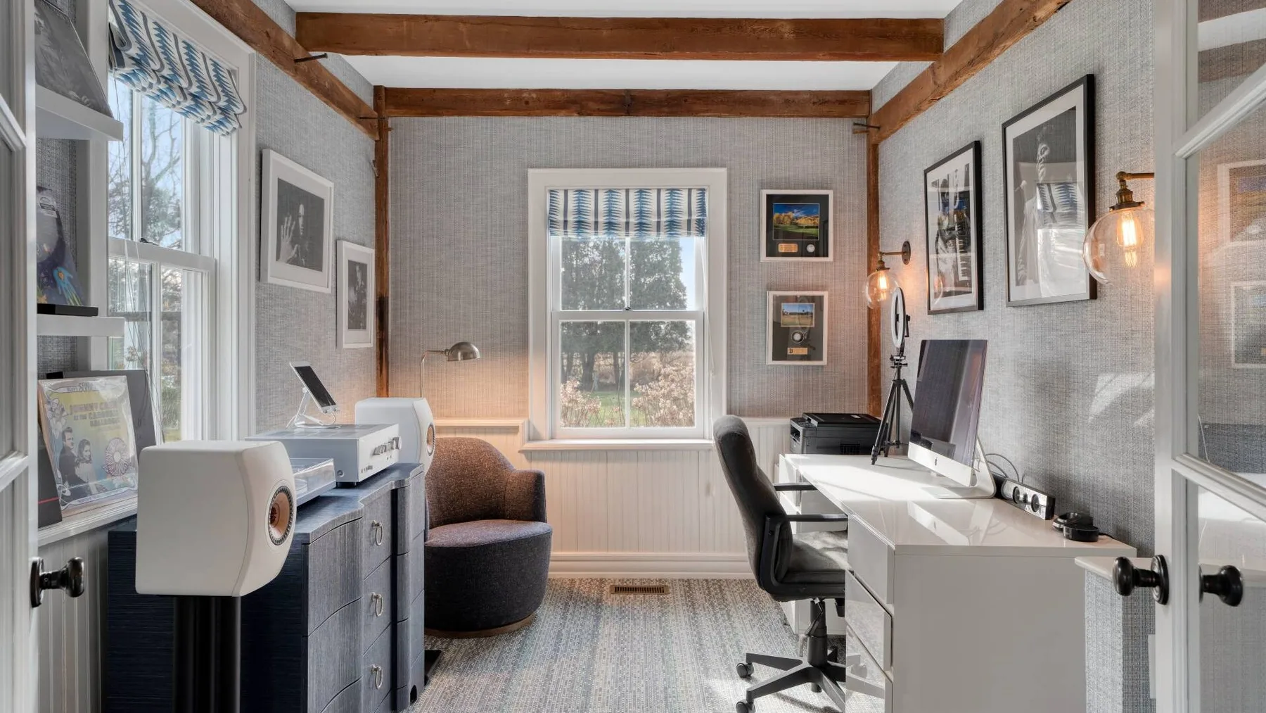 A bright home office with desks, computer monitors, and a window.