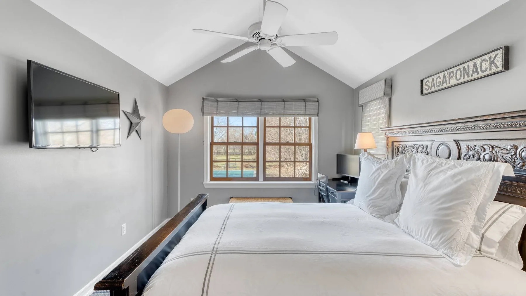 A bright bedroom with a large bed, a window, and a ceiling fan.