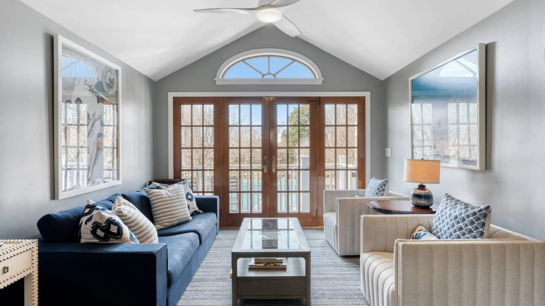 A bright living room with seating arranged around a coffee table and tall glass doors.