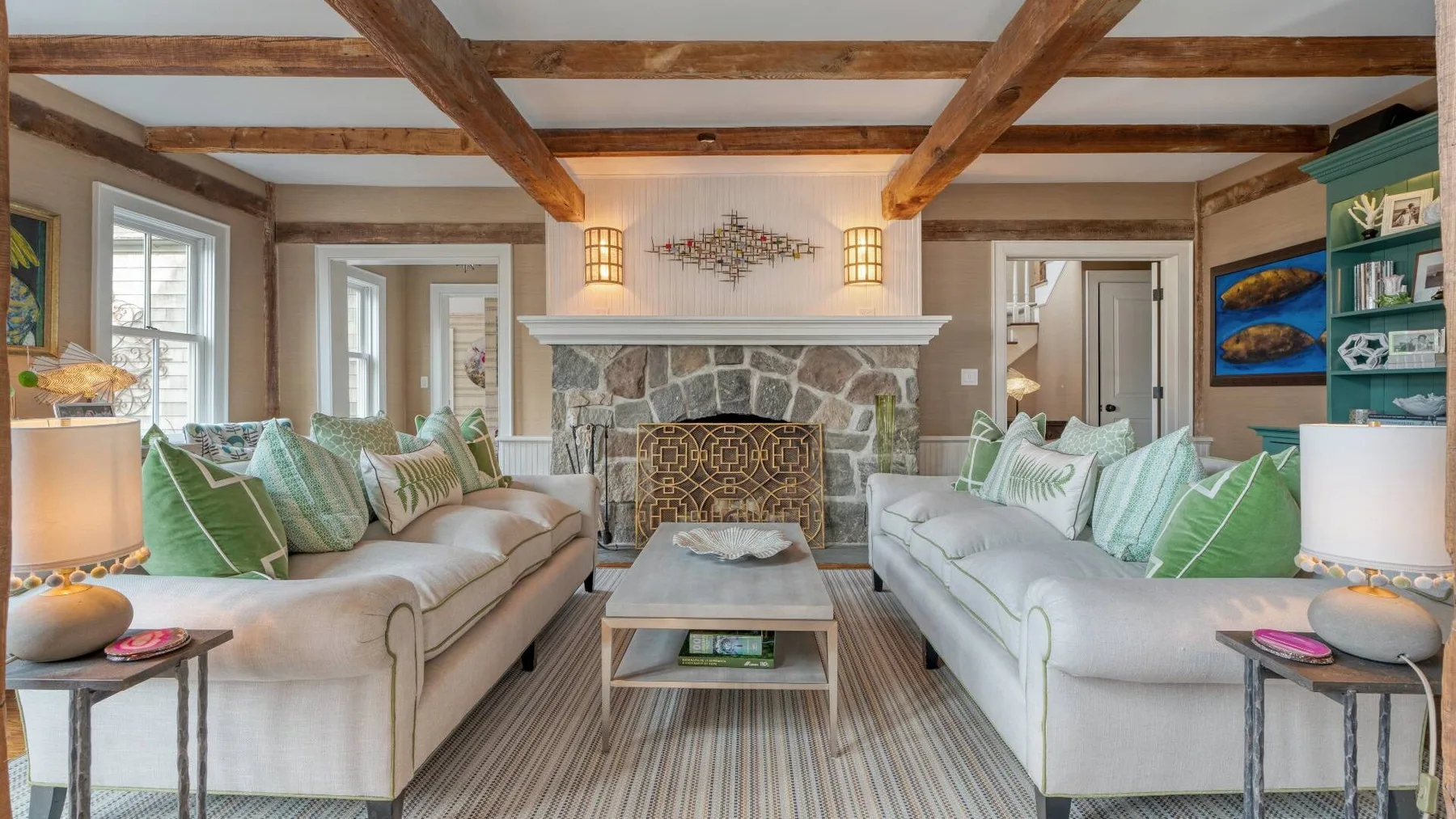 A living room with two seating areas facing a stone fireplace.