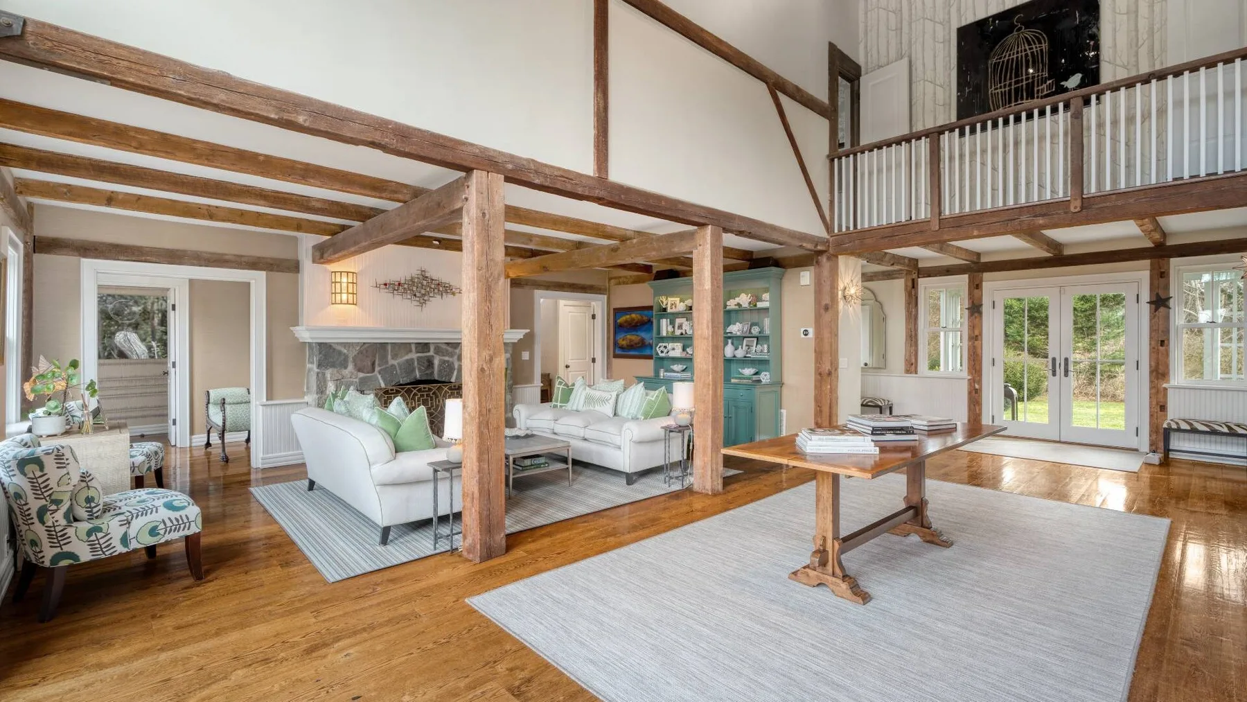 A spacious living room with seating, exposed wooden beams, and a mezzanine.