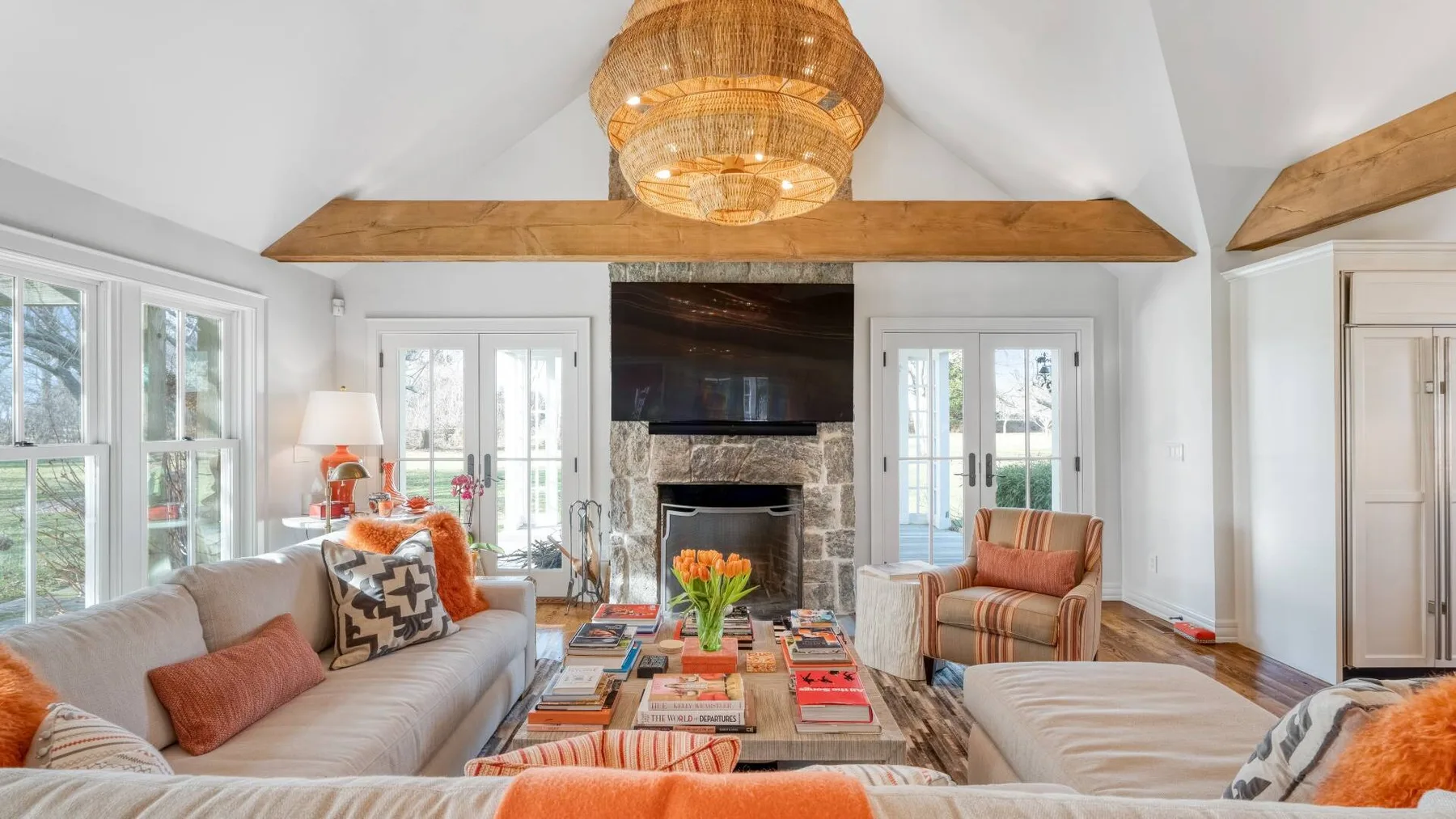 A bright living room with seating around a coffee table and a stone fireplace.