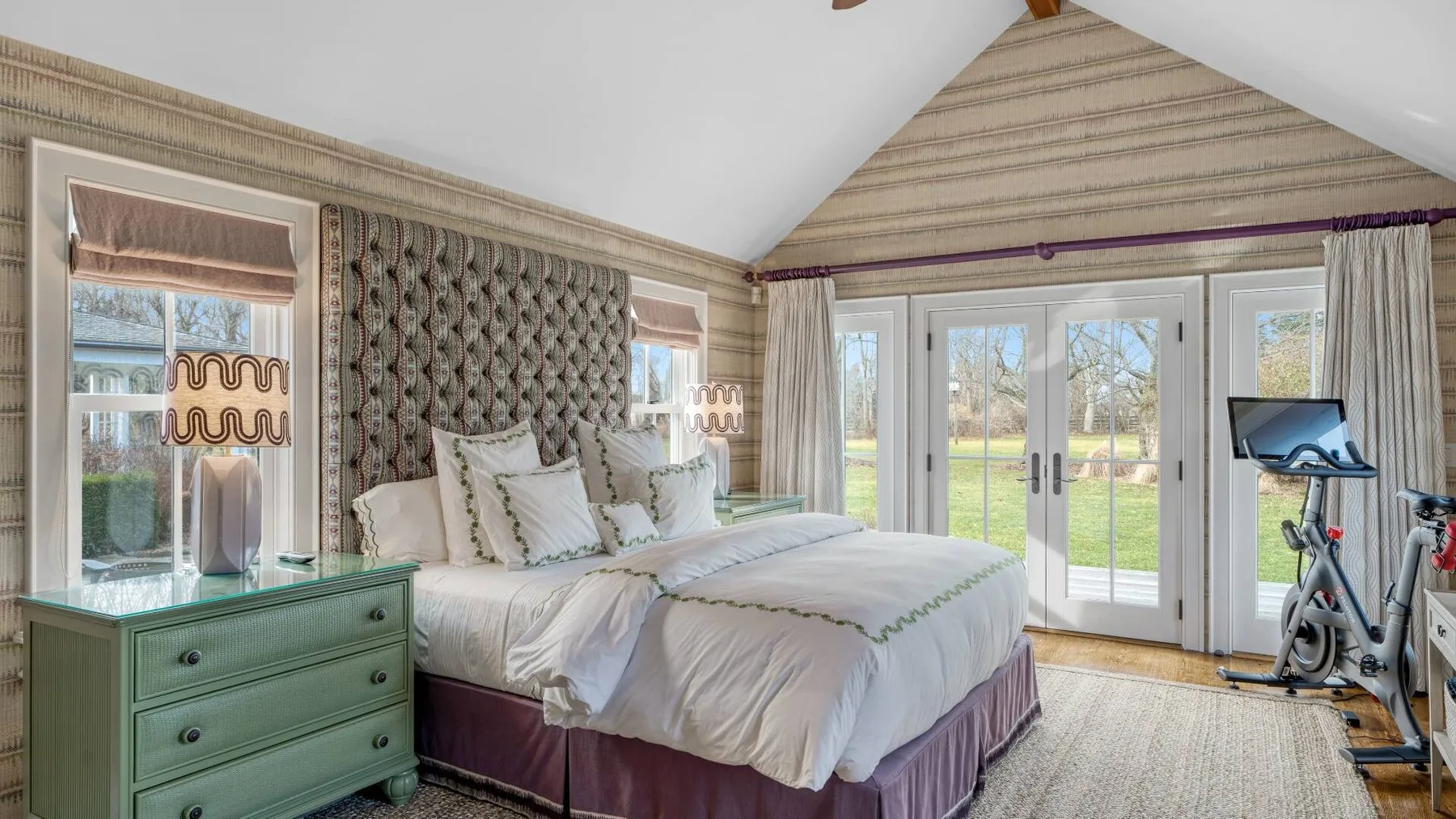A bedroom with a large bed, green dresser, and glass doors opening to a garden.