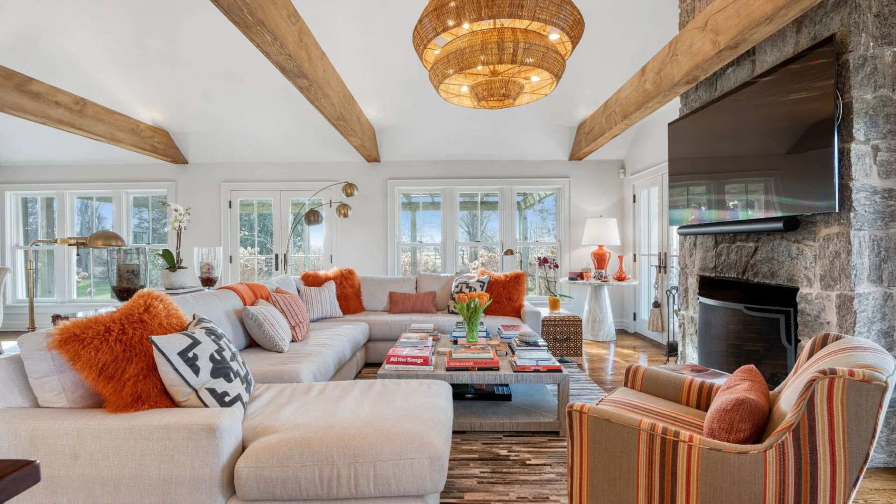 A bright living room with seating around a coffee table and a stone fireplace.