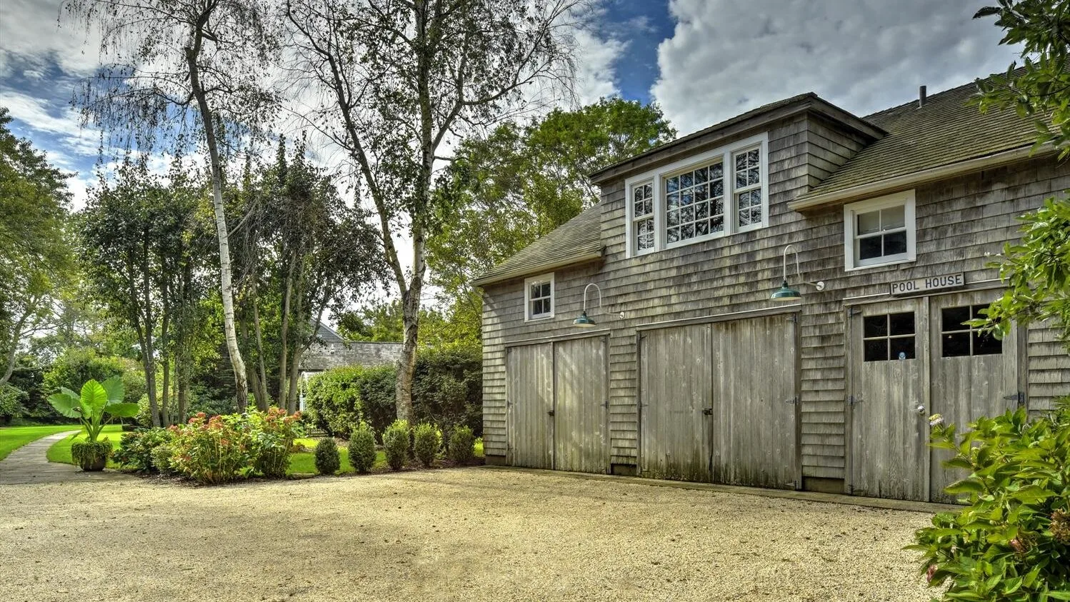 A weathered wooden outbuilding stands beside a landscaped garden.
