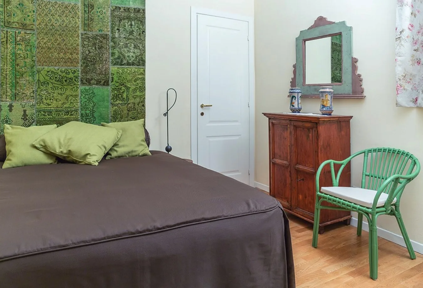 Un dormitorio con una cama, un mueble de madera y una silla verde.