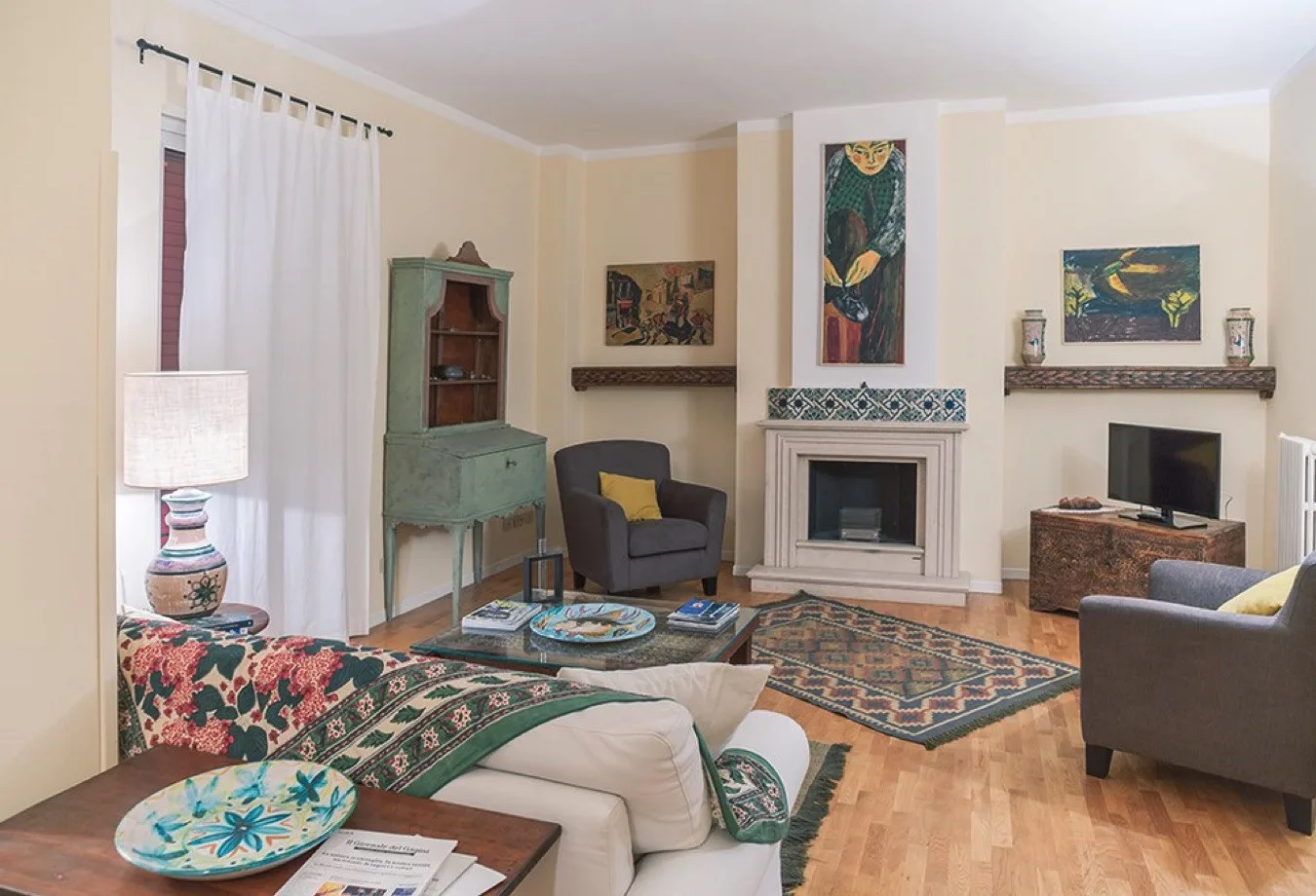 Una sala de estar con asientos, una chimenea y cuadros coloridos en las paredes.