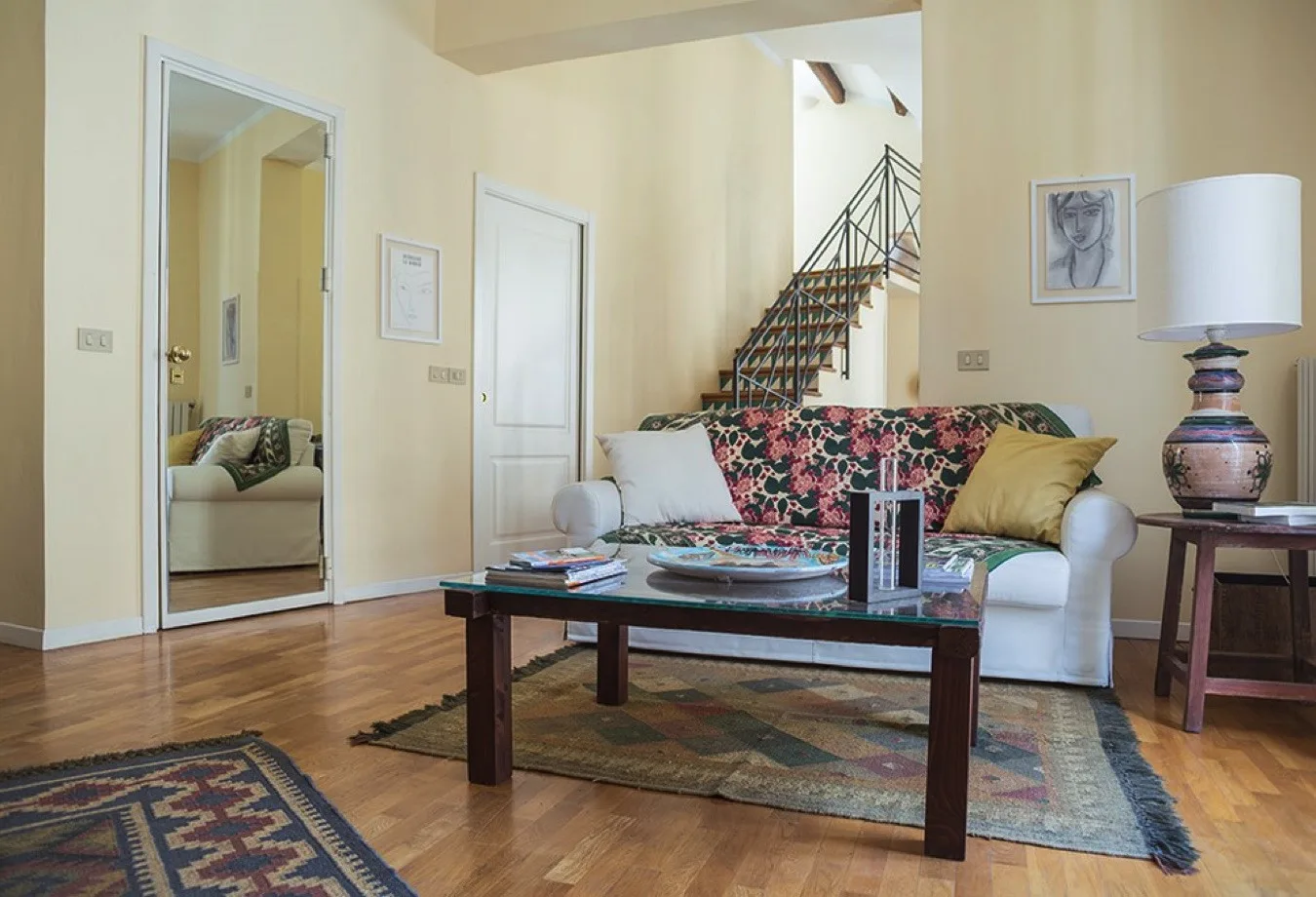Una sala de estar con un sofá floral, una mesa de centro y una escalera.