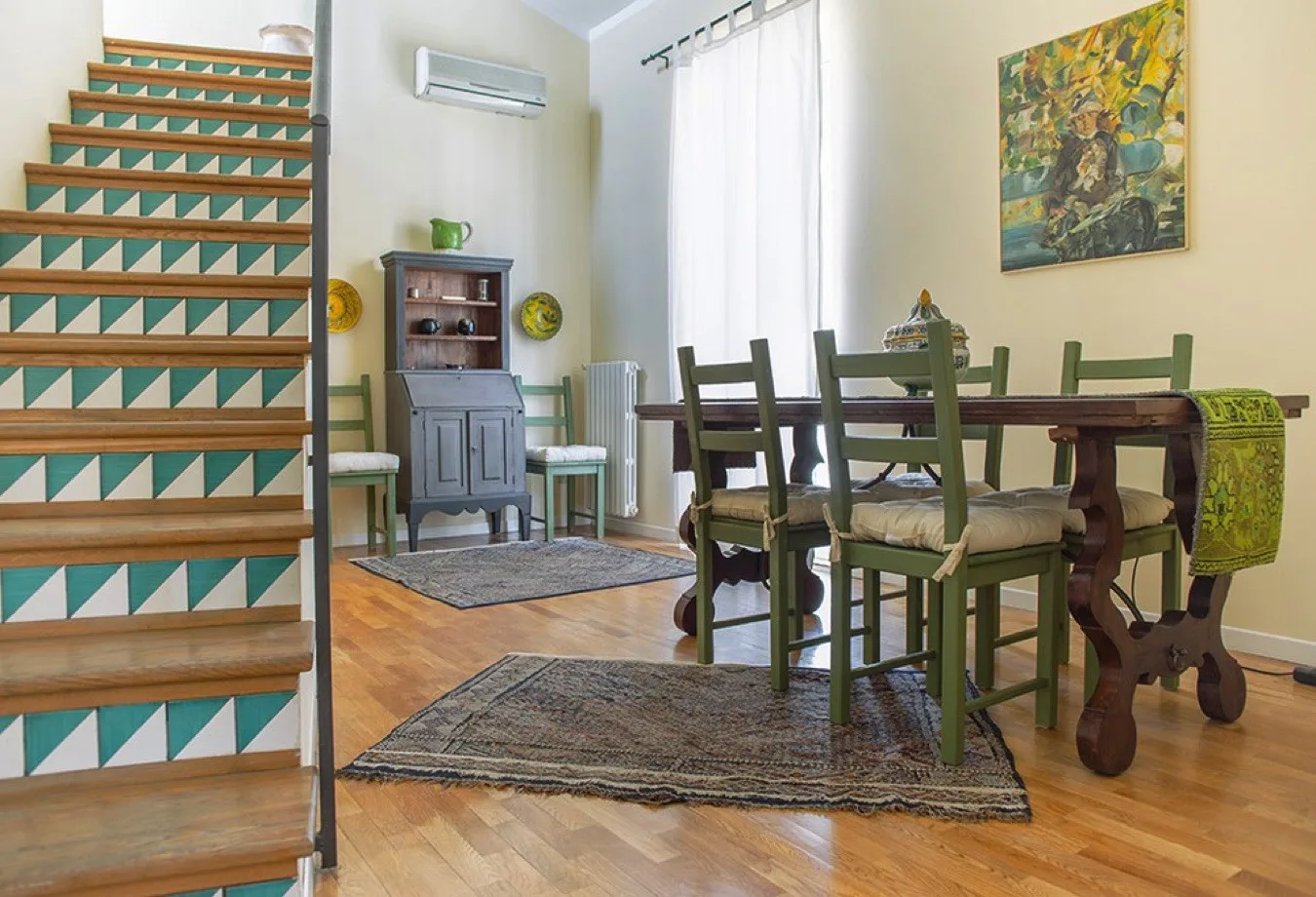 Comedor con una mesa de madera y sillas junto a una escalera.