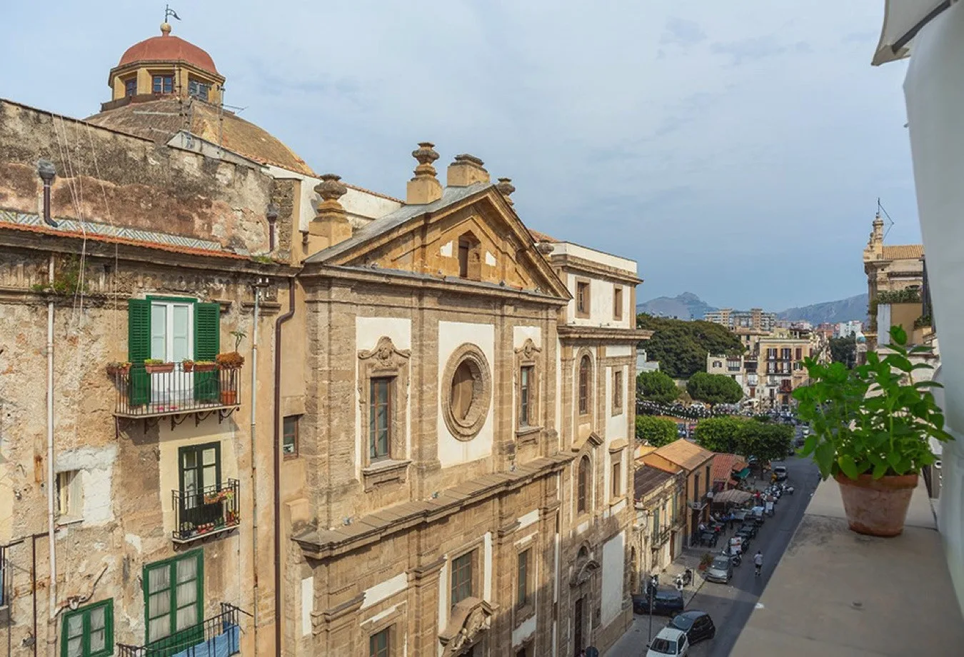 Edificios históricos de piedra bordean una calle urbana bajo un cielo azul claro.