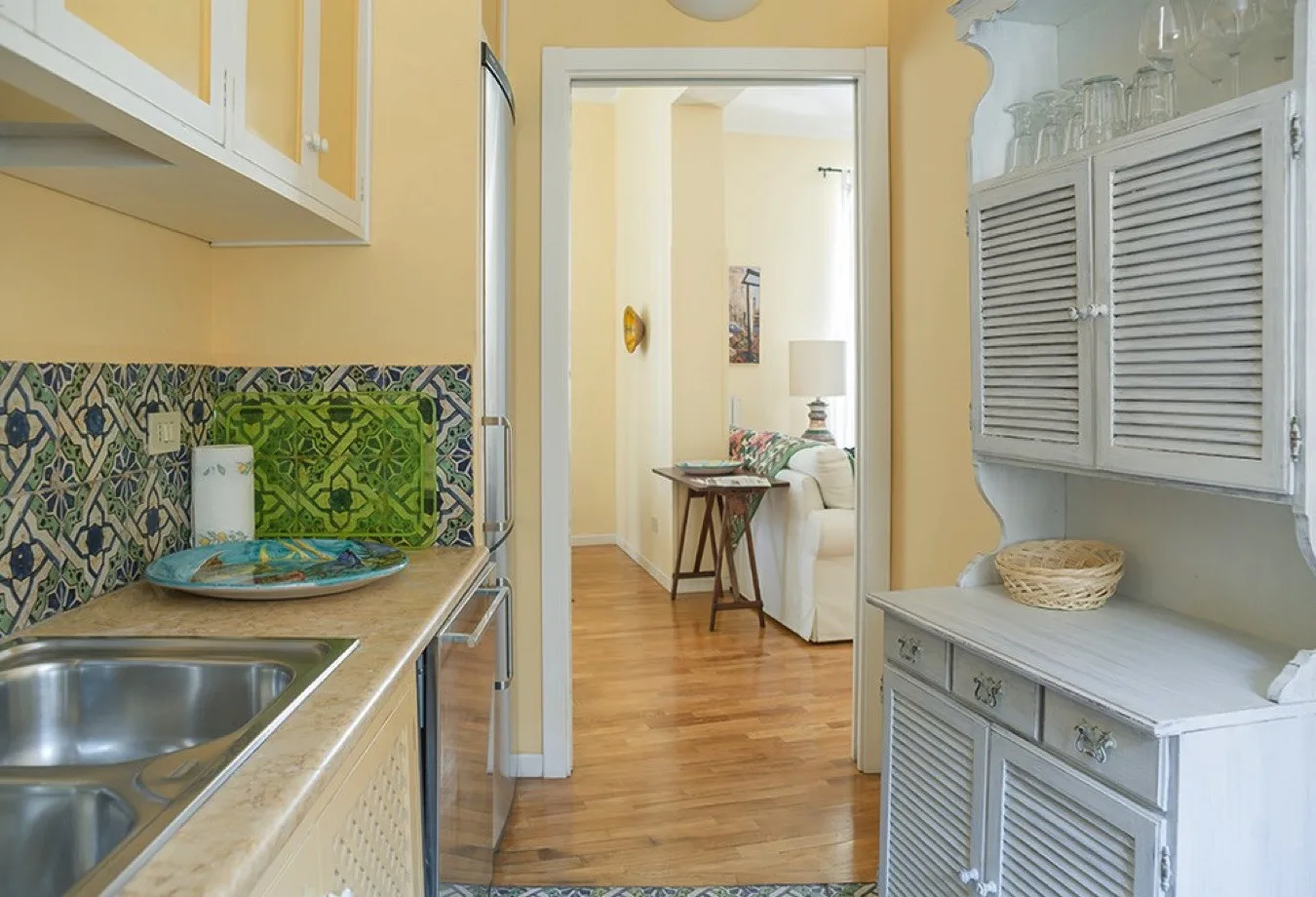 Una cocina compacta se abre a una sala de estar, con una encimera y suelo de madera.