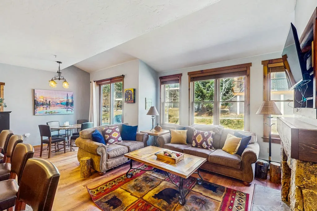A living room with seating, a coffee table, and large windows.