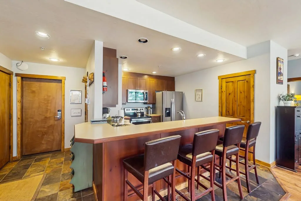 A kitchen with a long breakfast bar and several stools.