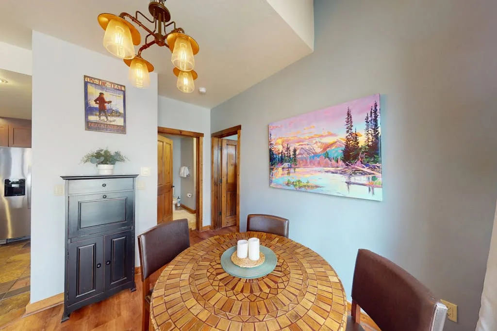 A dining area with a round wooden table beneath a hanging light.