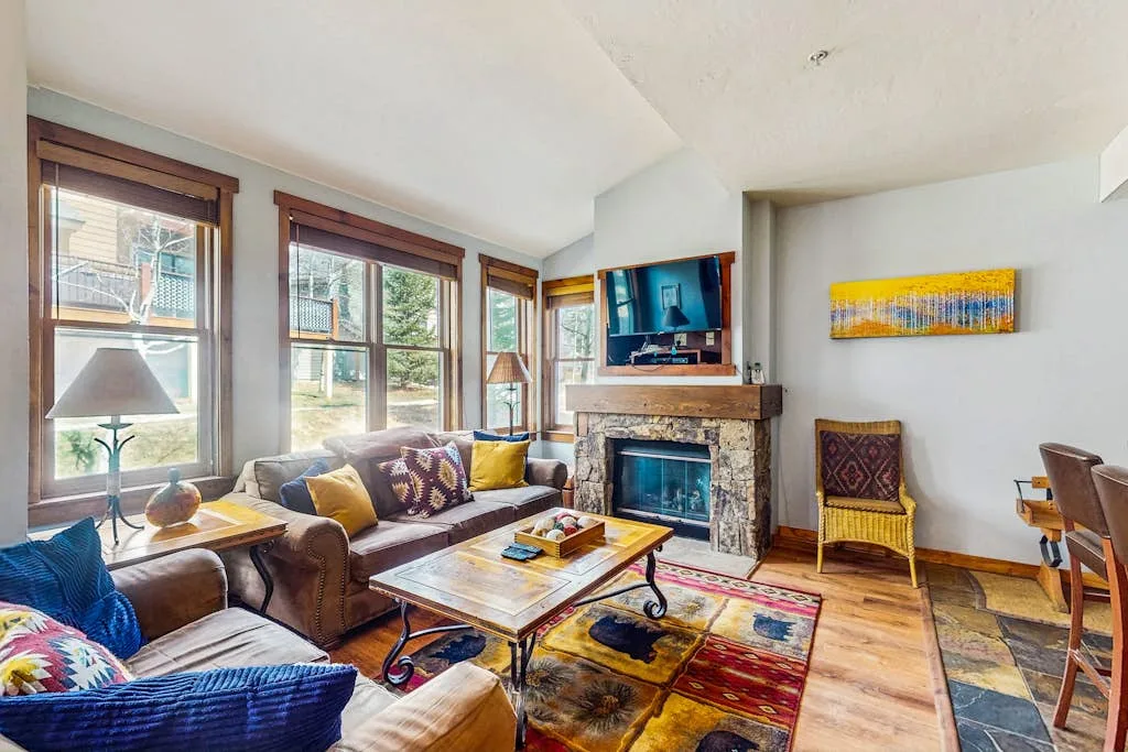 A bright living room with seating arranged around a fireplace and coffee table.