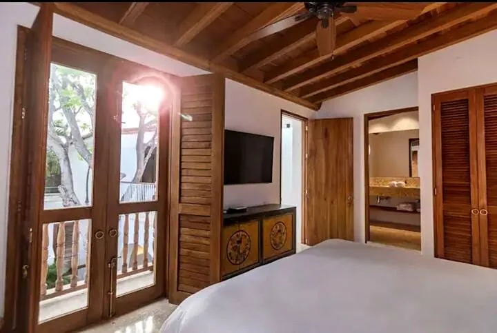 Un dormitorio con puertas de madera, un televisor y vista a una habitación contigua.