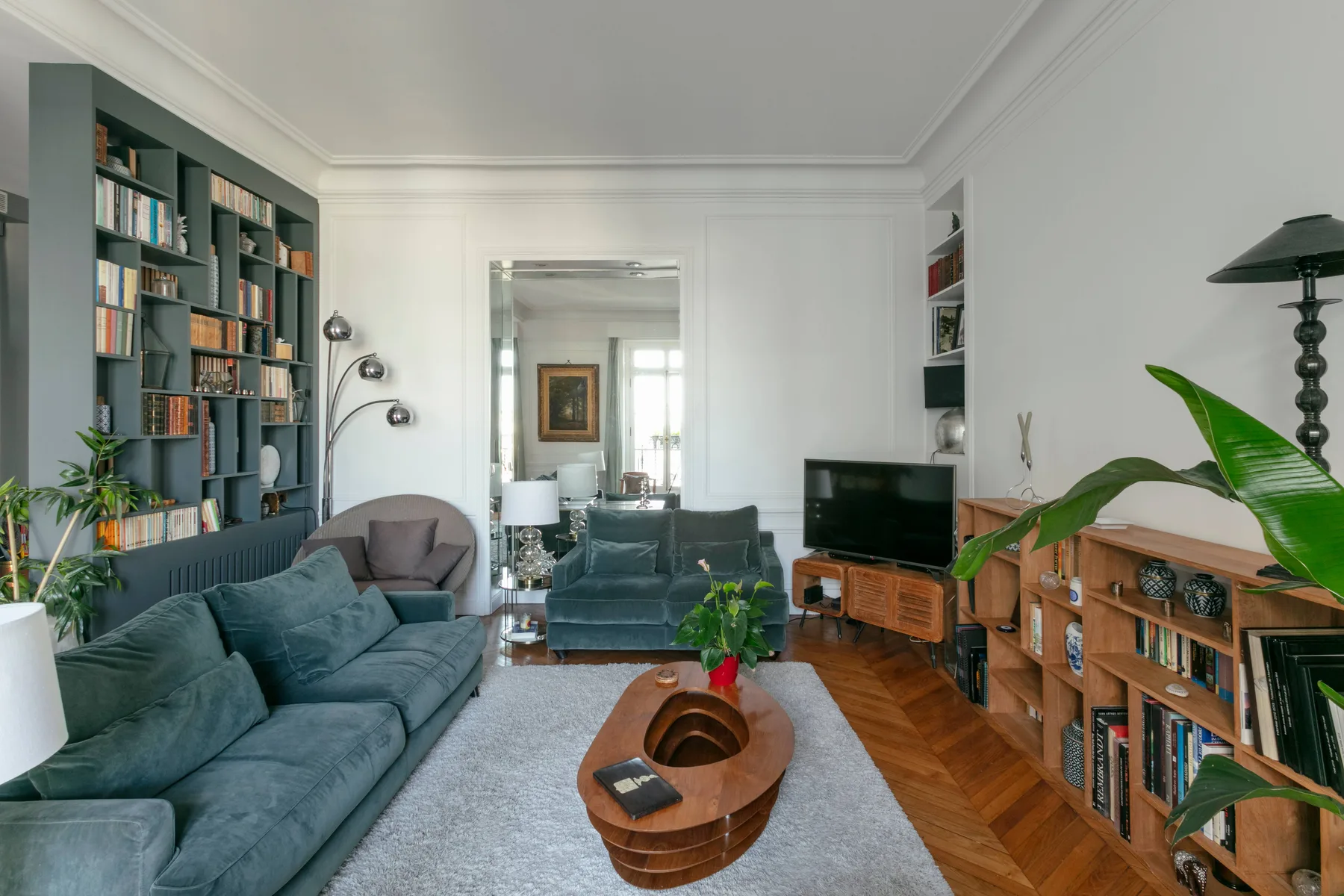 Una sala luminosa con asientos azules, estanterías y una mesa de centro de madera.