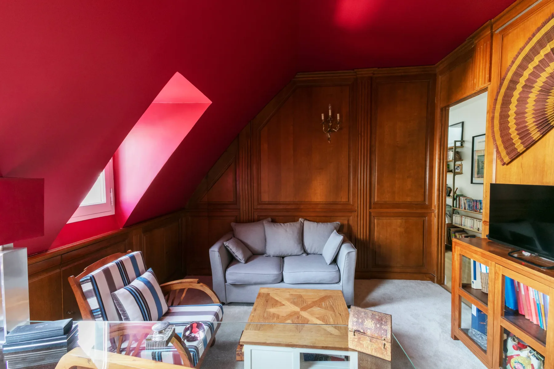 Una sala de estar con paredes revestidas de madera y un sofá gris.