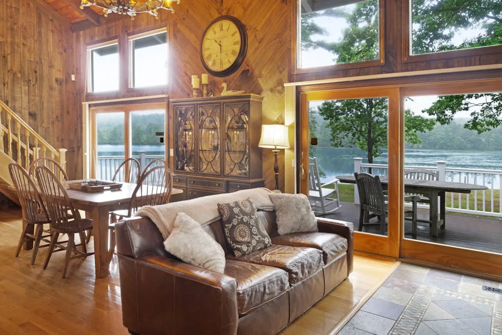 A wood-paneled living and dining area opens onto a deck overlooking the water.