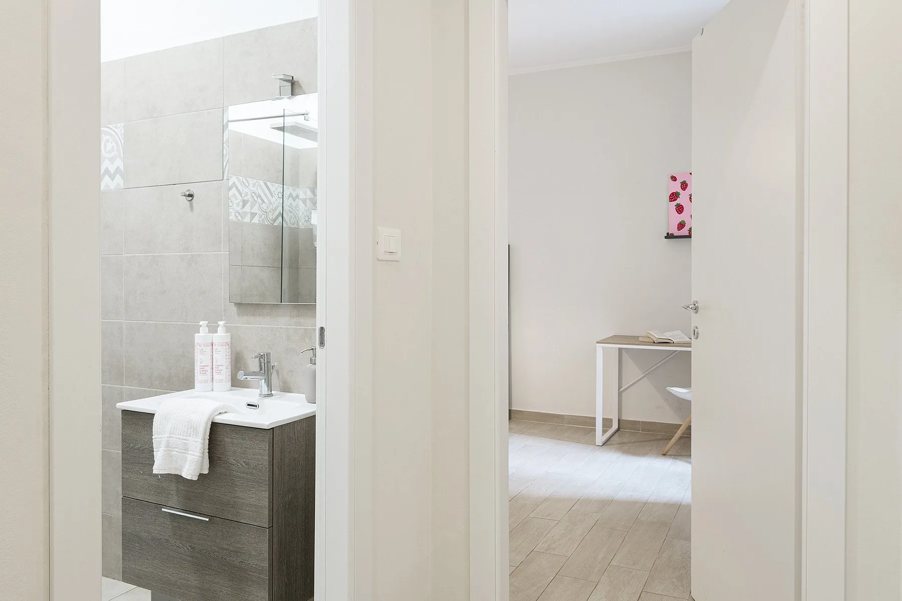 An open doorway shows a bathroom vanity beside a sparsely furnished room.