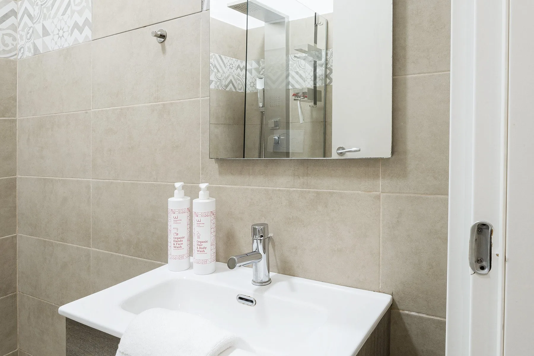 A bathroom vanity with a white sink, chrome faucet, and wall mirror.