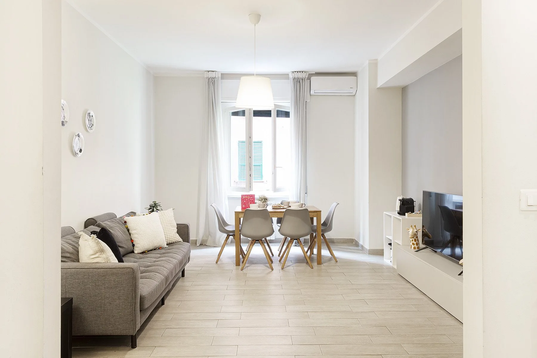 A bright living and dining area with seating, a table, and a television.