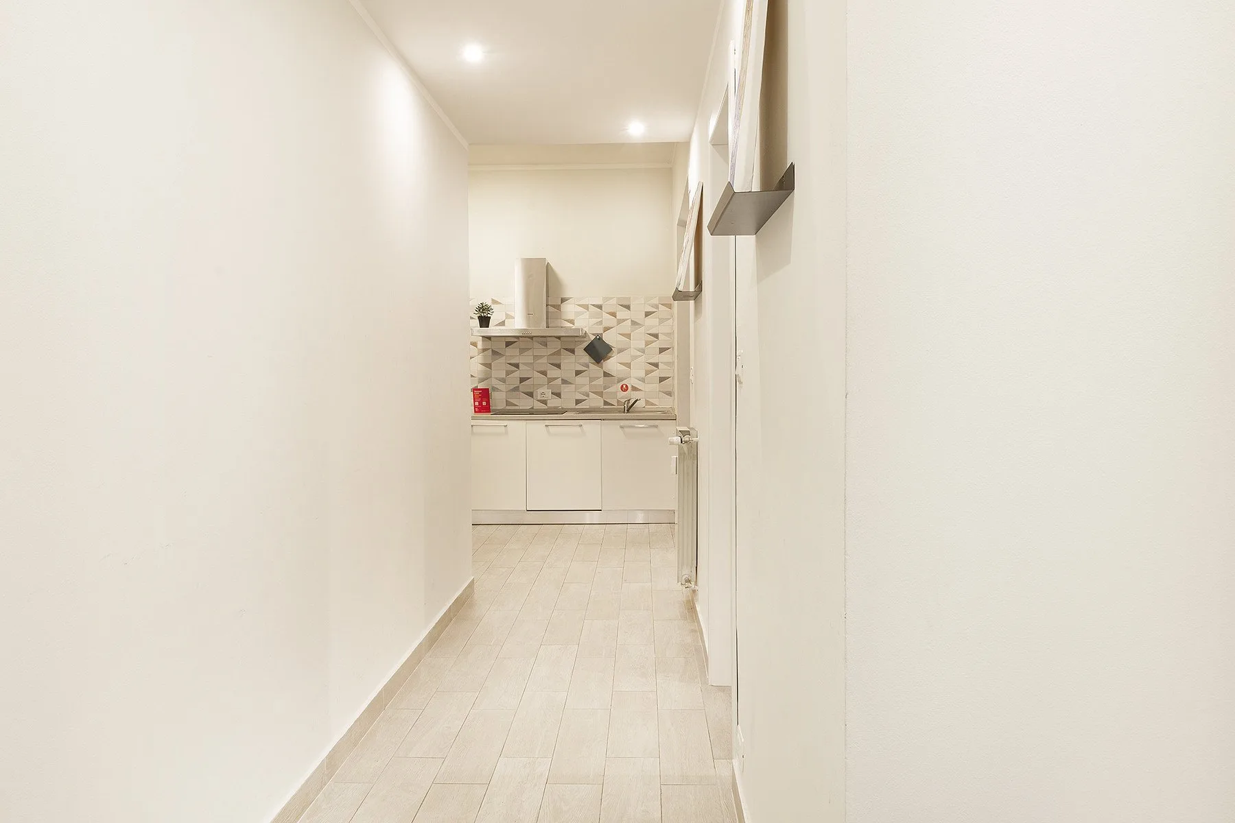 A narrow kitchen corridor leads to a counter with a tiled backsplash.