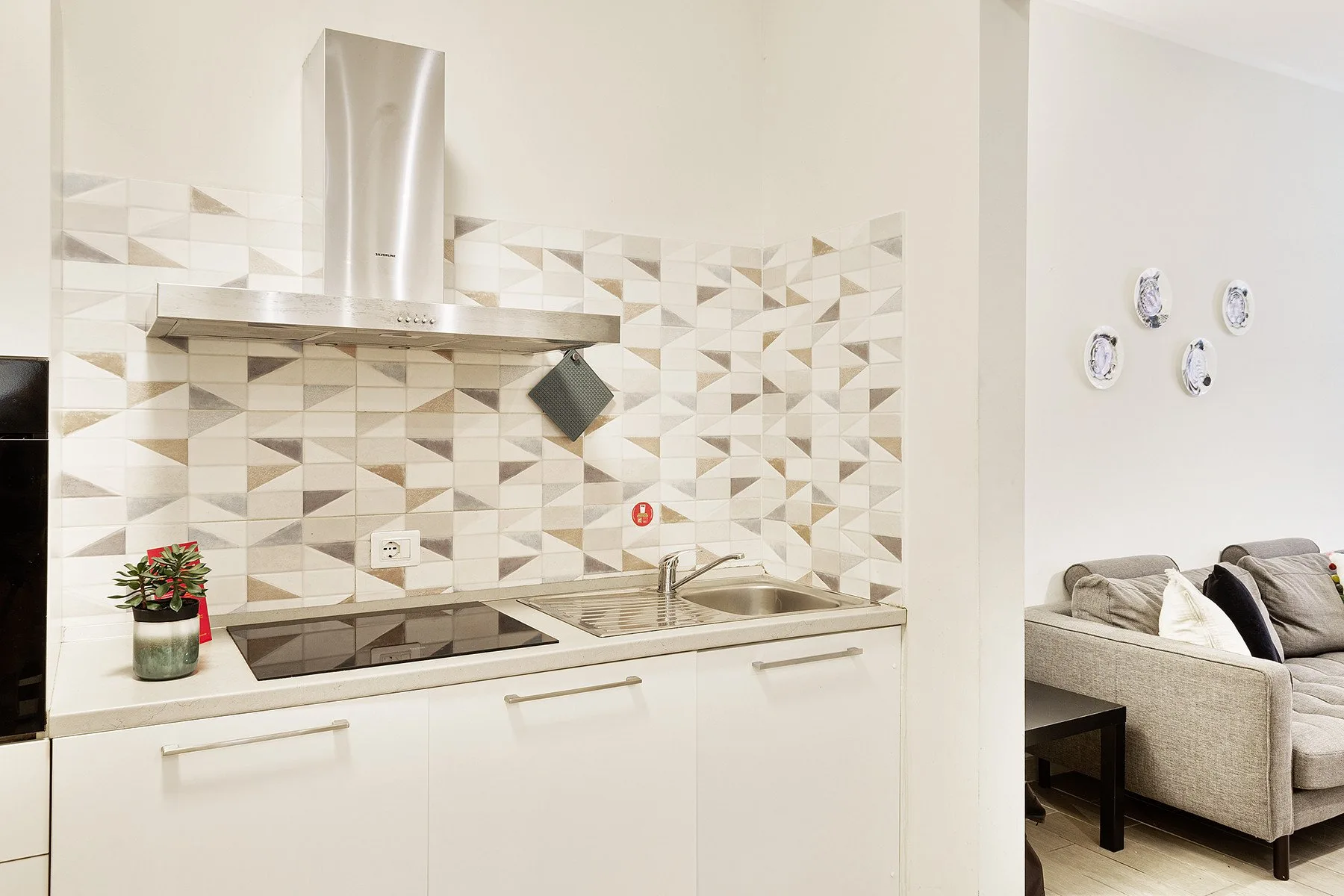 A bright kitchen with a patterned backsplash and an adjacent seating area.