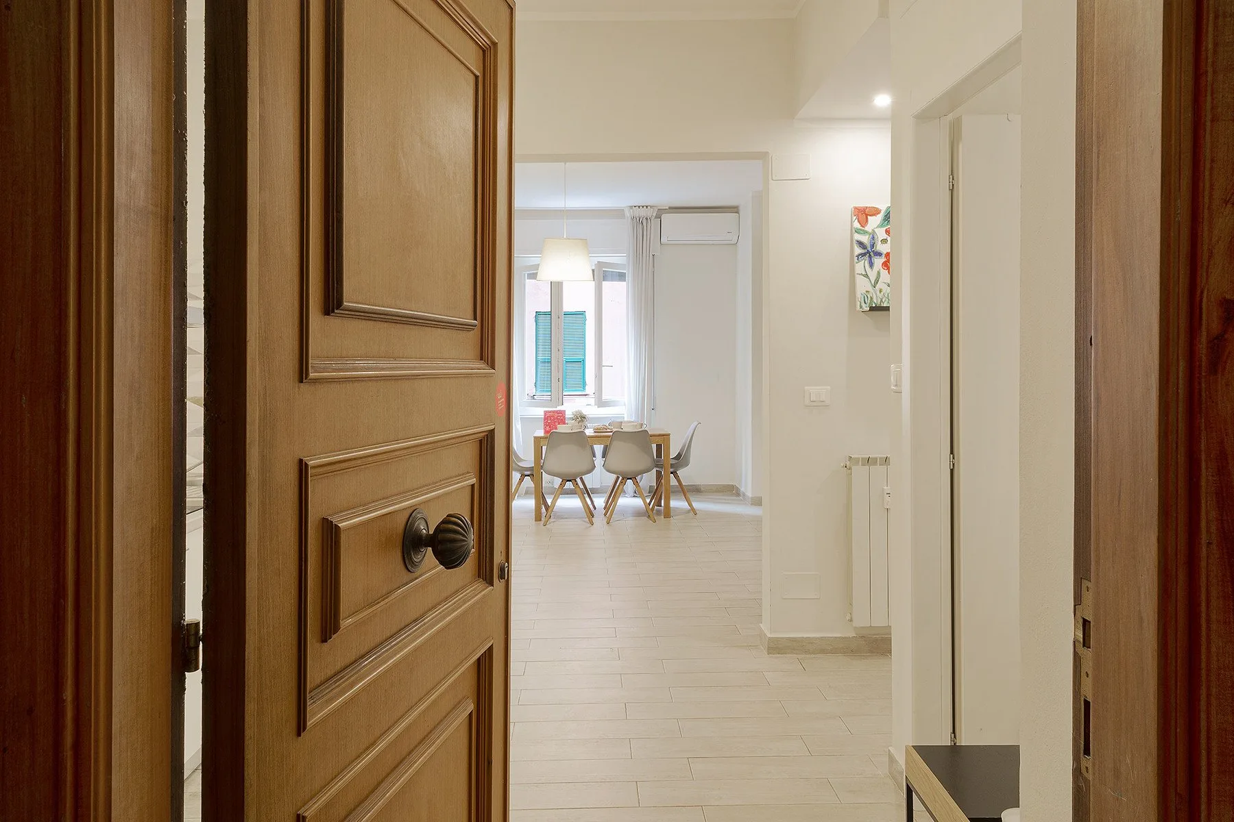 An interior hallway opens onto a bright dining area with a table and chairs.