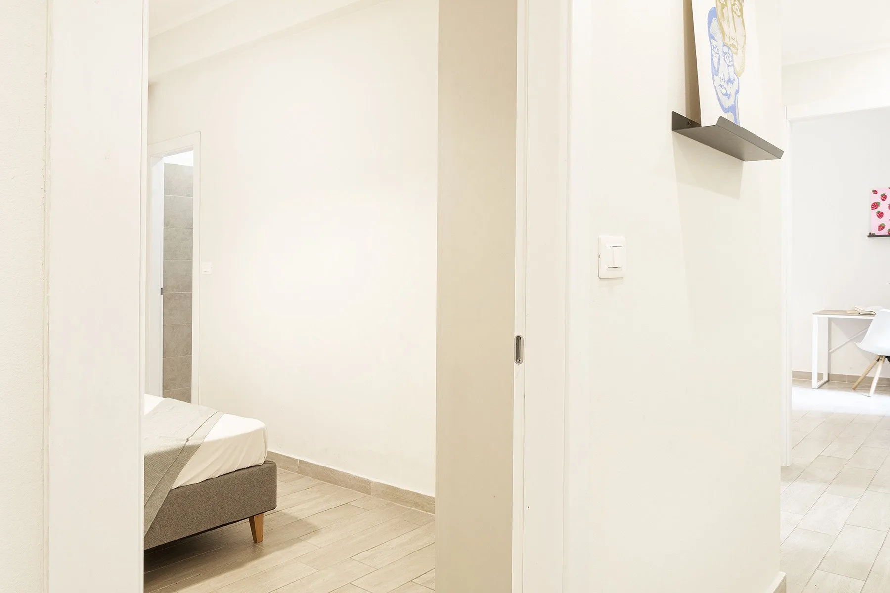 A bright bedroom with a bed beside an open doorway.